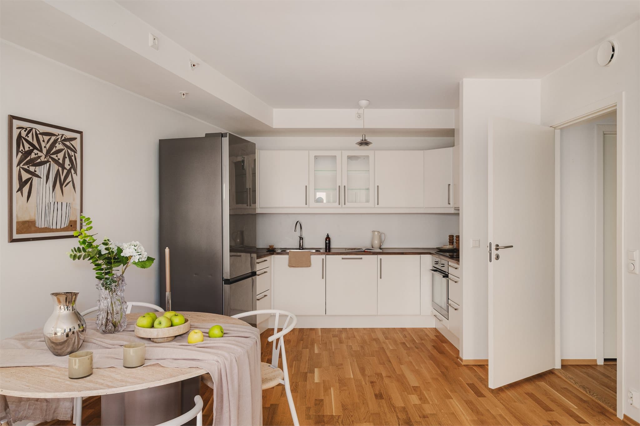 - Designa kjøkkeninnredning med slette hvite fronter, overskap med glassfronter, benkeplate i laminat, underlimt stål vaskekum og ventilator -
