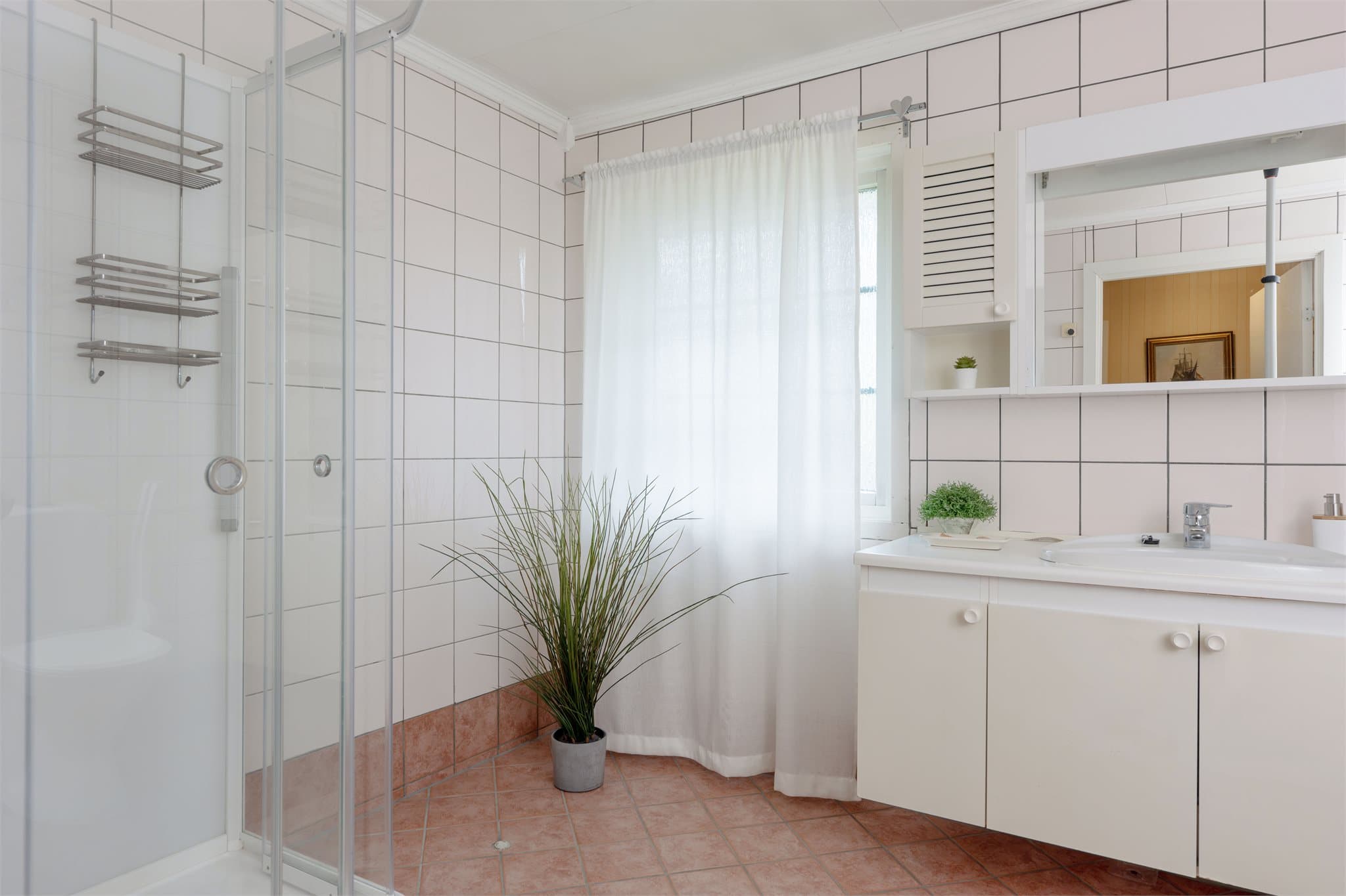 Badet har flislagte vegger og naturlig tilluft via vindu og luftespalte.