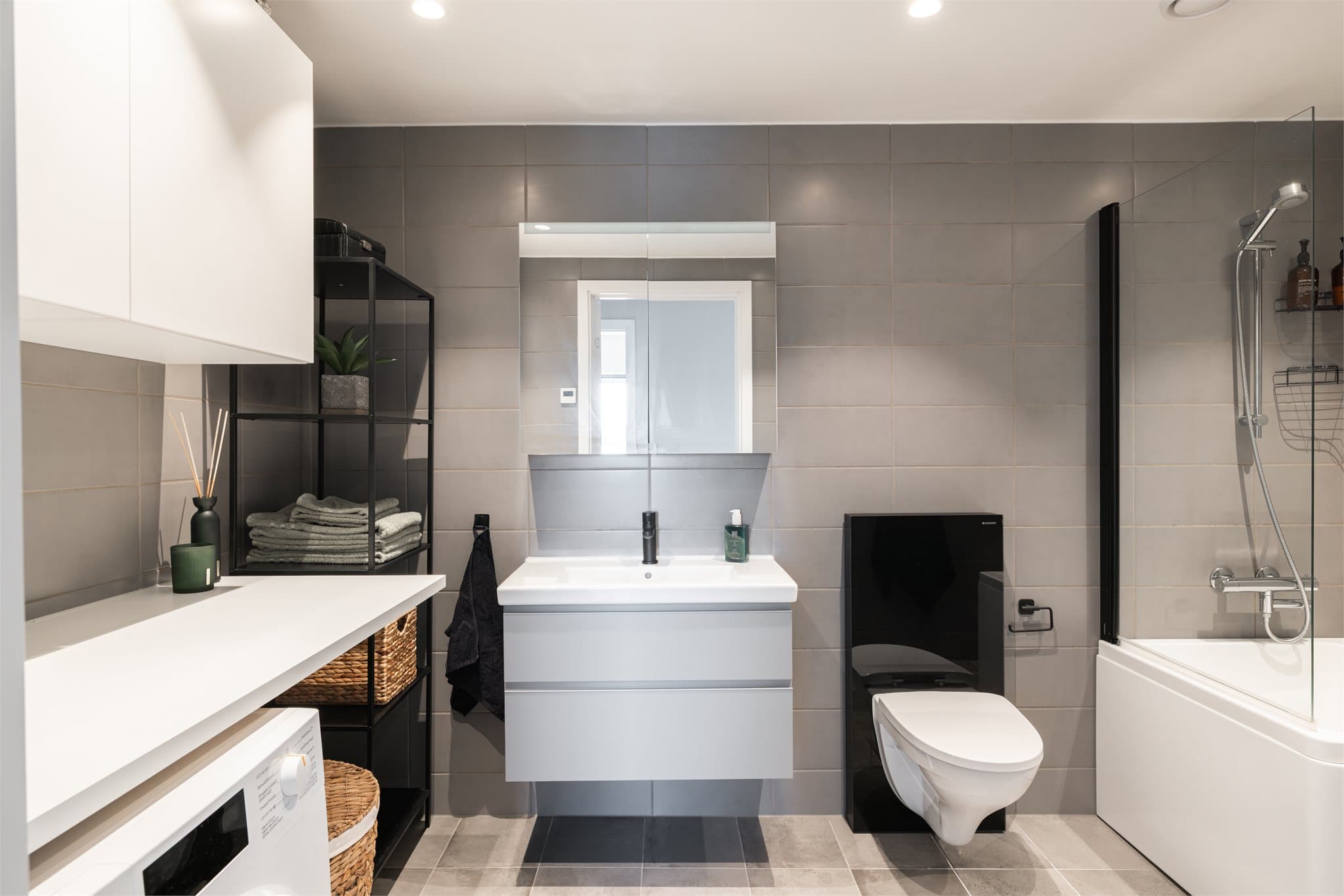 Pent flislagt baderom/vaskerom. Mørke30x30cm fliser på gulv med varme og mørke 40x20 på vegger.