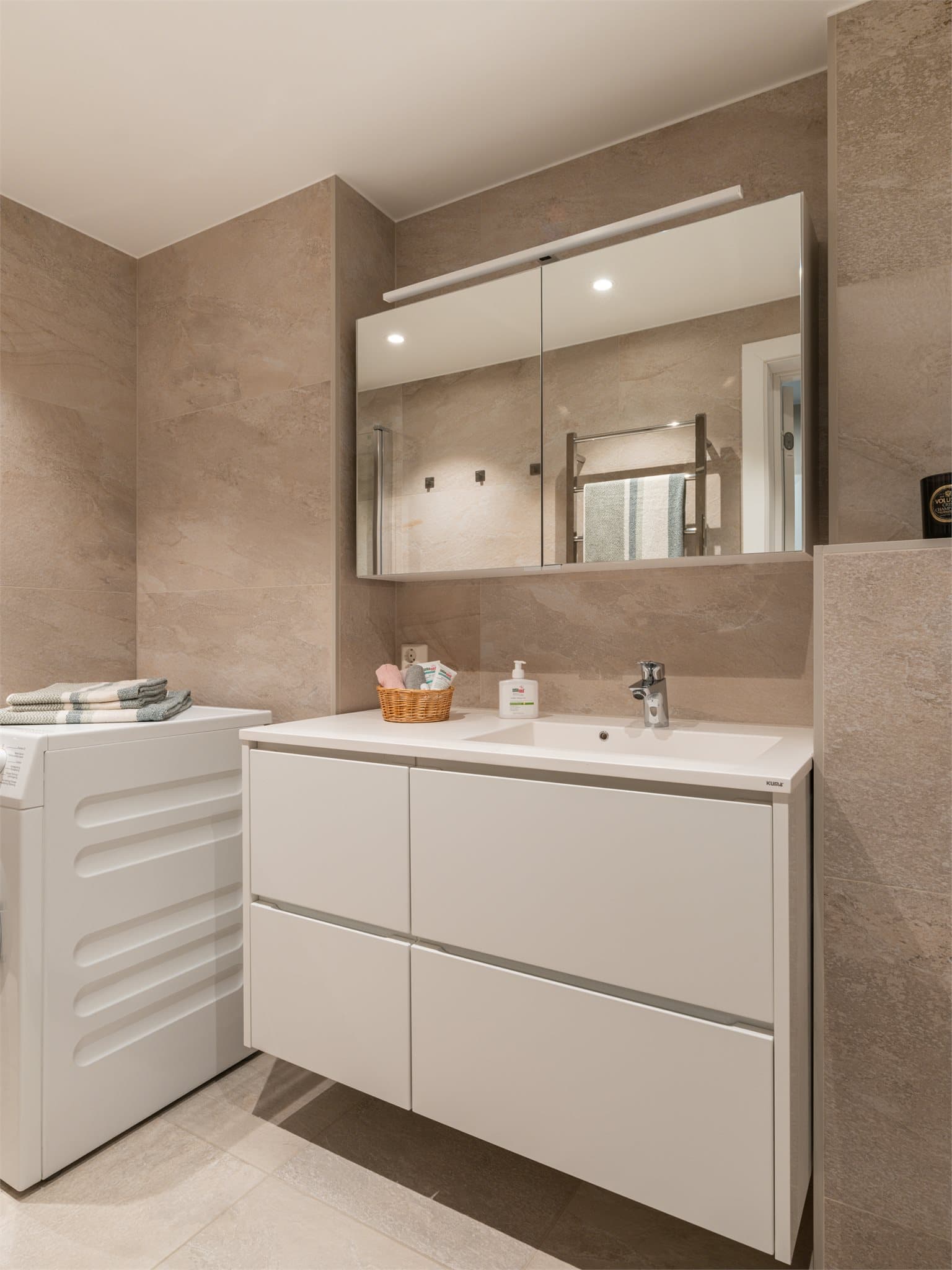 Innredningen inkluderer en servant med skuffer, speilskap og vegghengt toalett med innebygget sisterne.