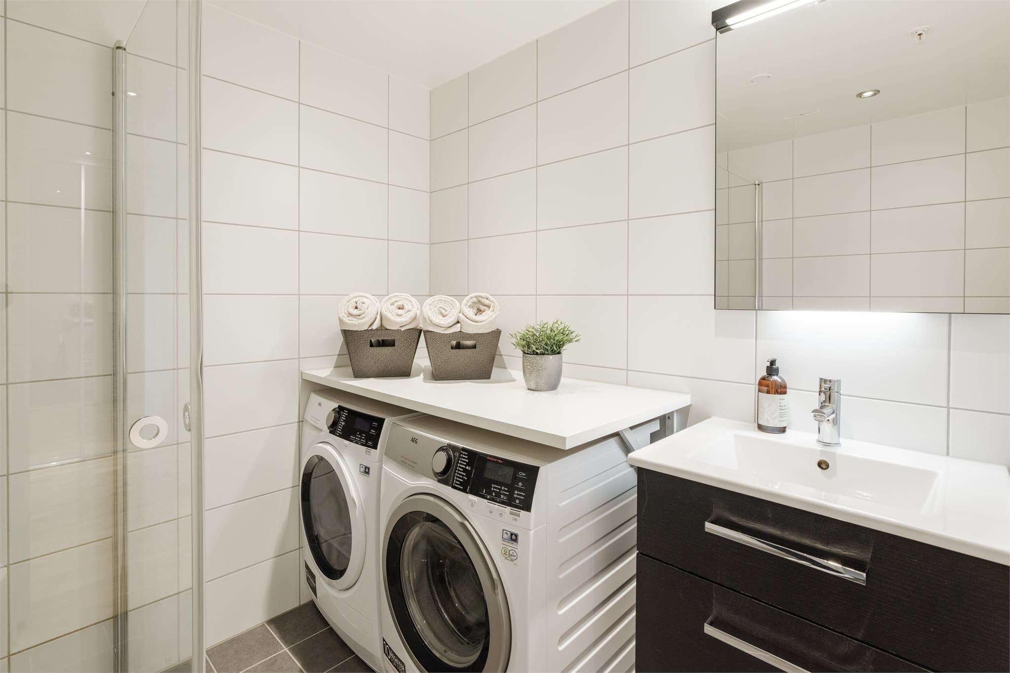 Innredningen består av servantskap med mørke trefronter, samt helstøpt, hvit servant med tilhørende kromfarget ettgreps blandebatteri.