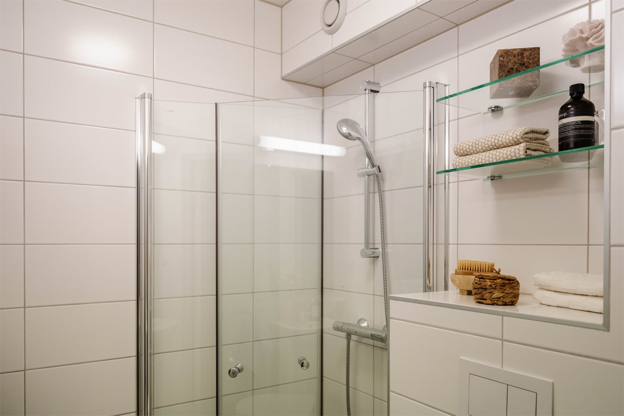 Badet har vegghengt toalett og elektriske varmekabler under de mørke gulvflisene.