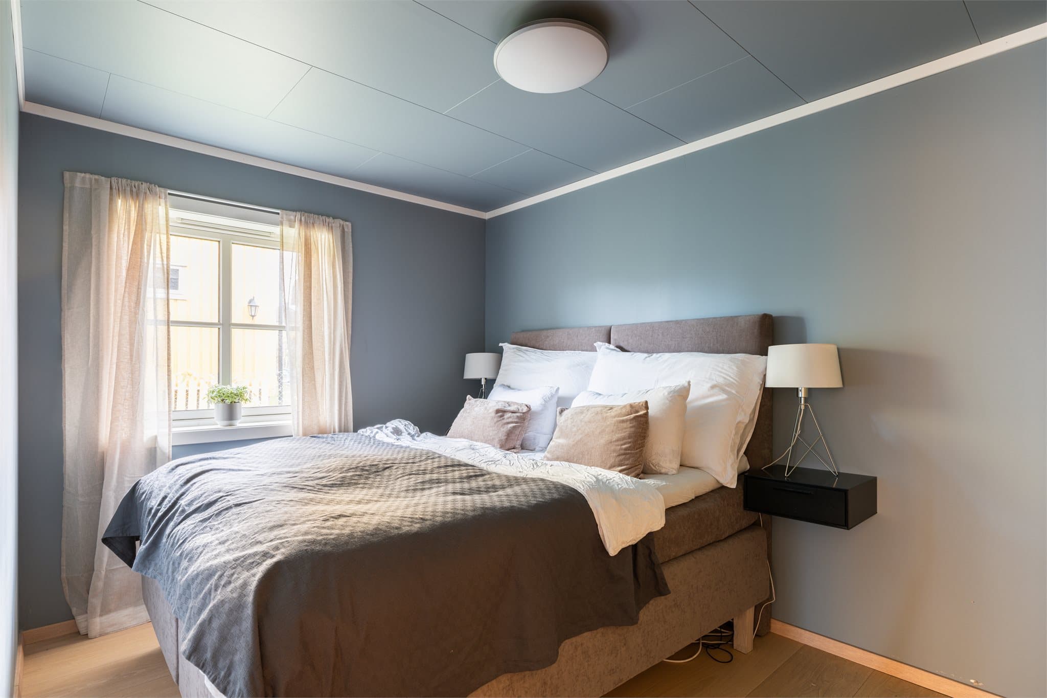 Rommet har god plass til en stor seng og vegghengte nattbord som gir et rent og moderne uttrykk.