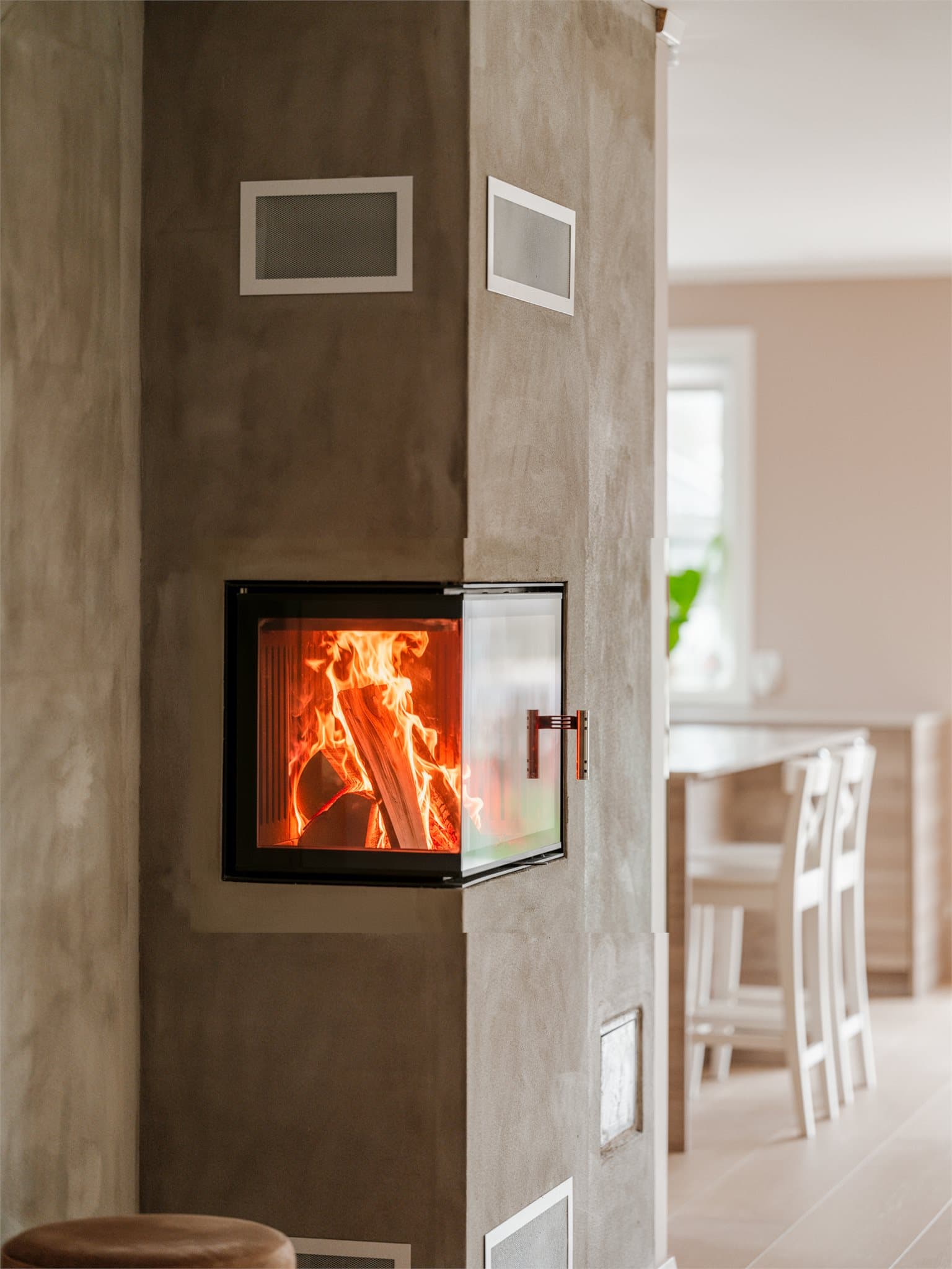 Den moderne peisen markerer overgangen mellom stue og kjøkken og bidrar til en lun og eksklusiv stemning.