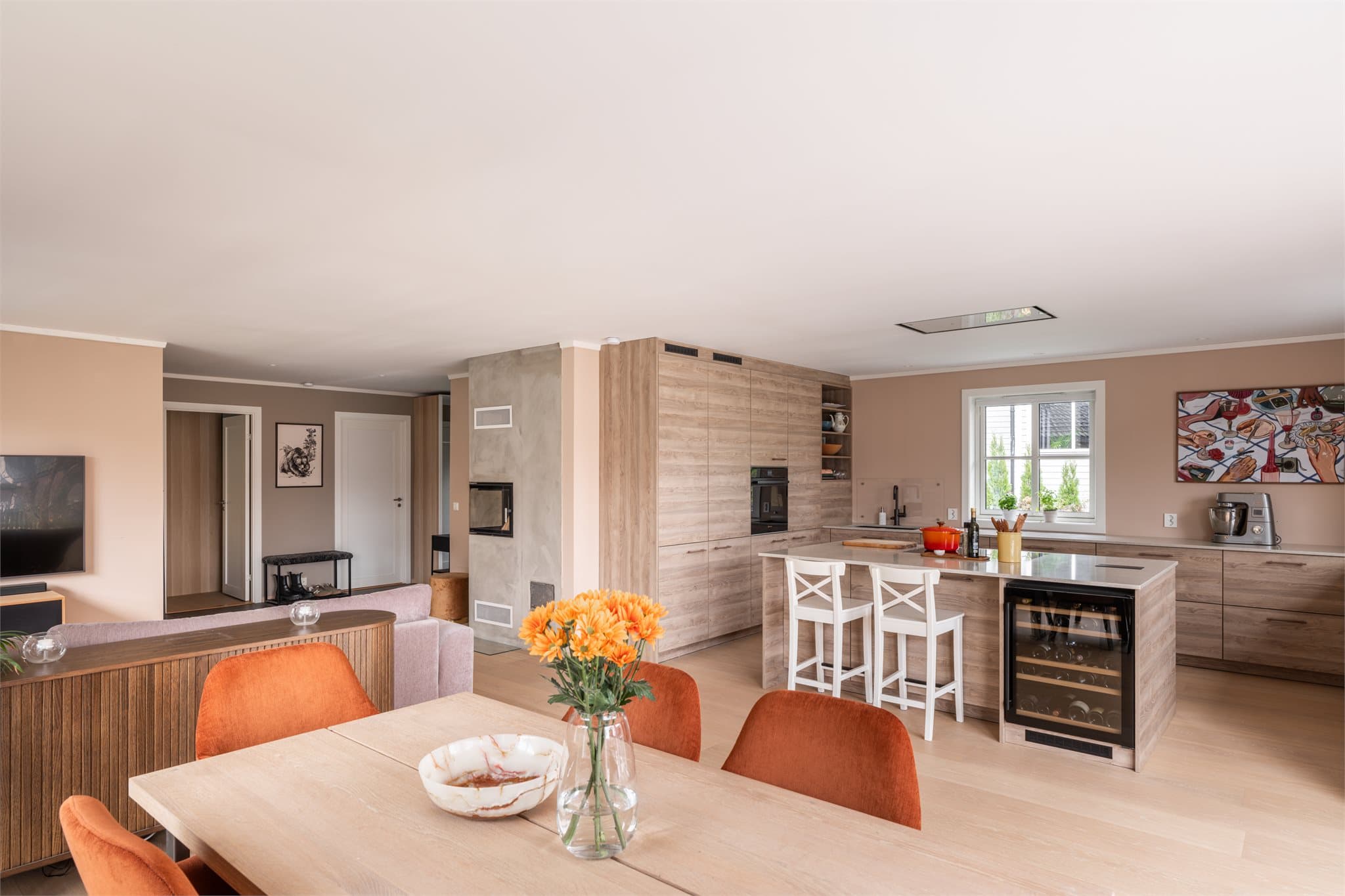 Den åpne løsningen gir en sosial atmosfære der kjøkken, spiseplass og stue smelter naturlig sammen.