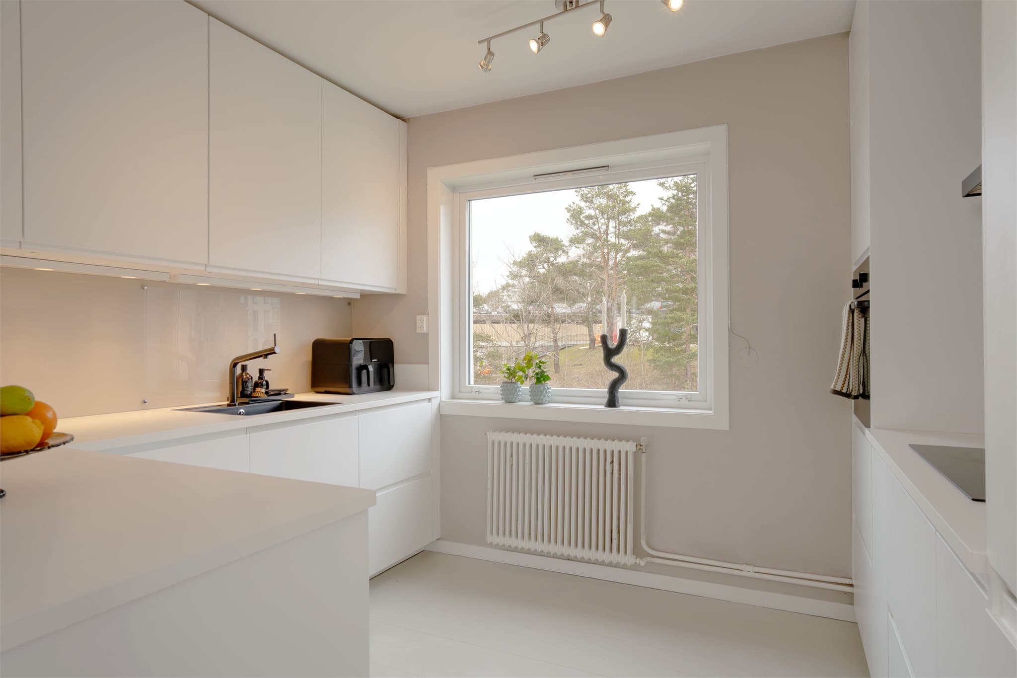 Moderne kjøkken med rikelig benke- og skapplass. Radiatoren under vinduet er koblet til fellesanlegget for vannbåren varme.