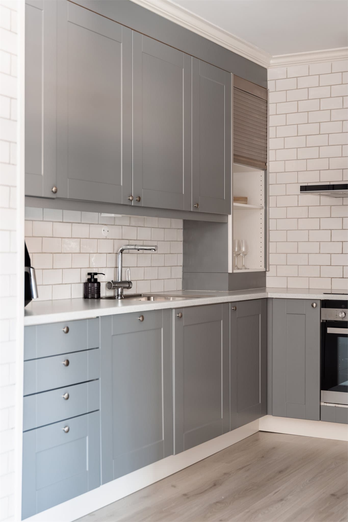 Kjøkkeninnredningen har glatte, grå fronter og en slitesterk, lys laminatbenkeplate.