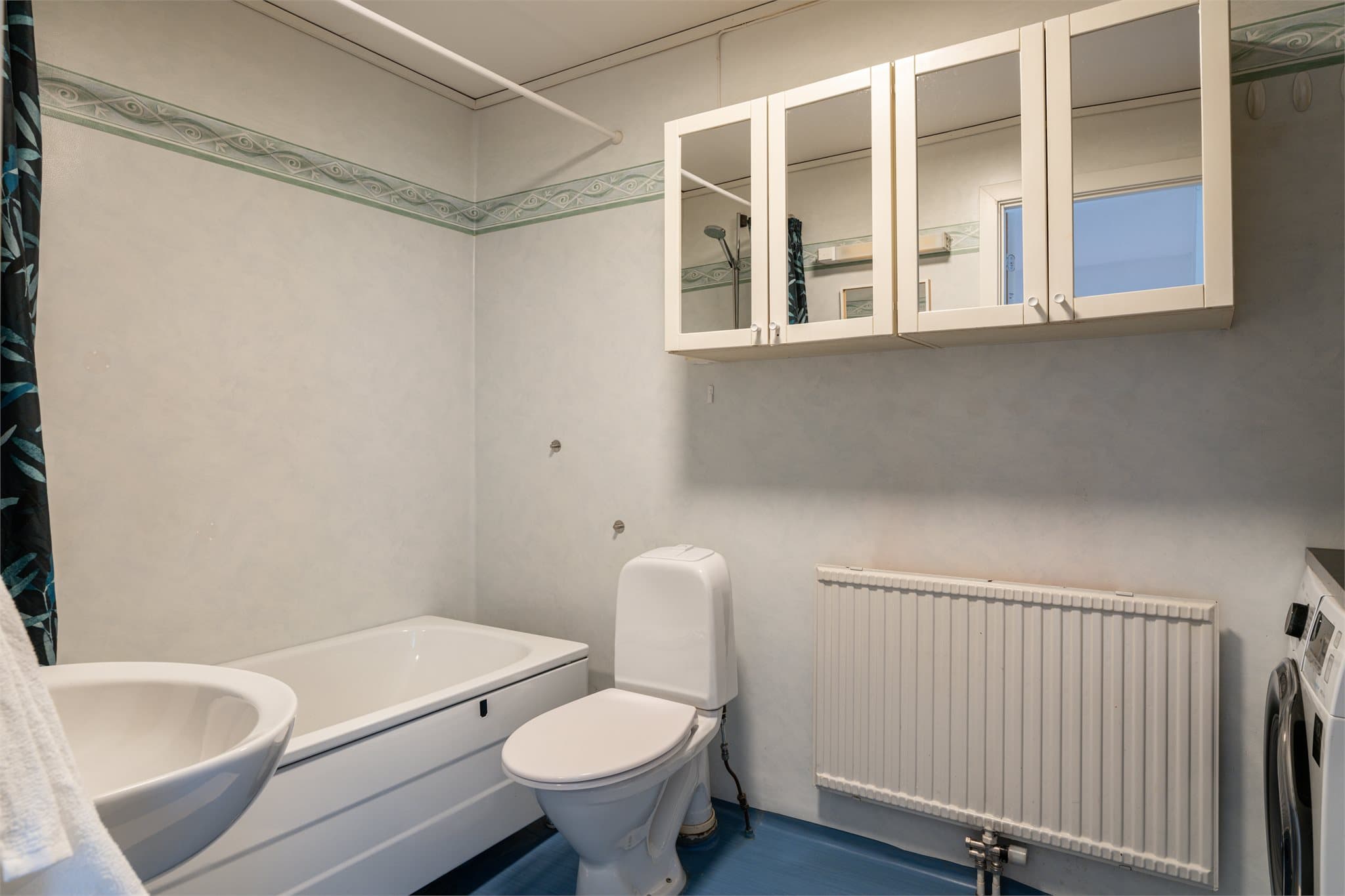 Videre er badet innredet med badekar, toalett og servant.