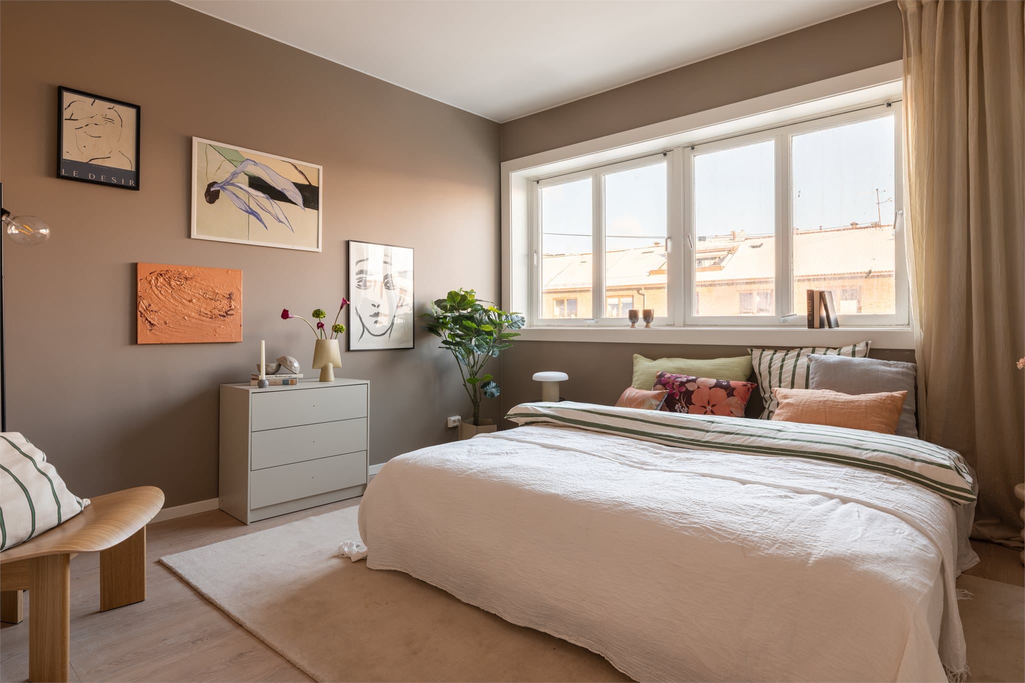 Lunt og luftig hovedsoverom med mye naturlig lys fra store vinduer.