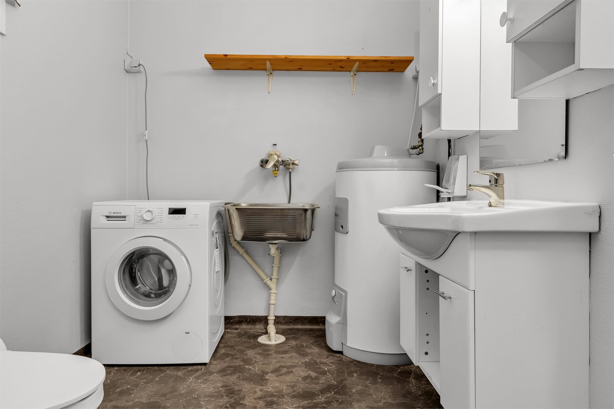 Praktisk løsning med vaskeromsdel på badet. Varmtvannsberederen på 188 liter er fra 2019.