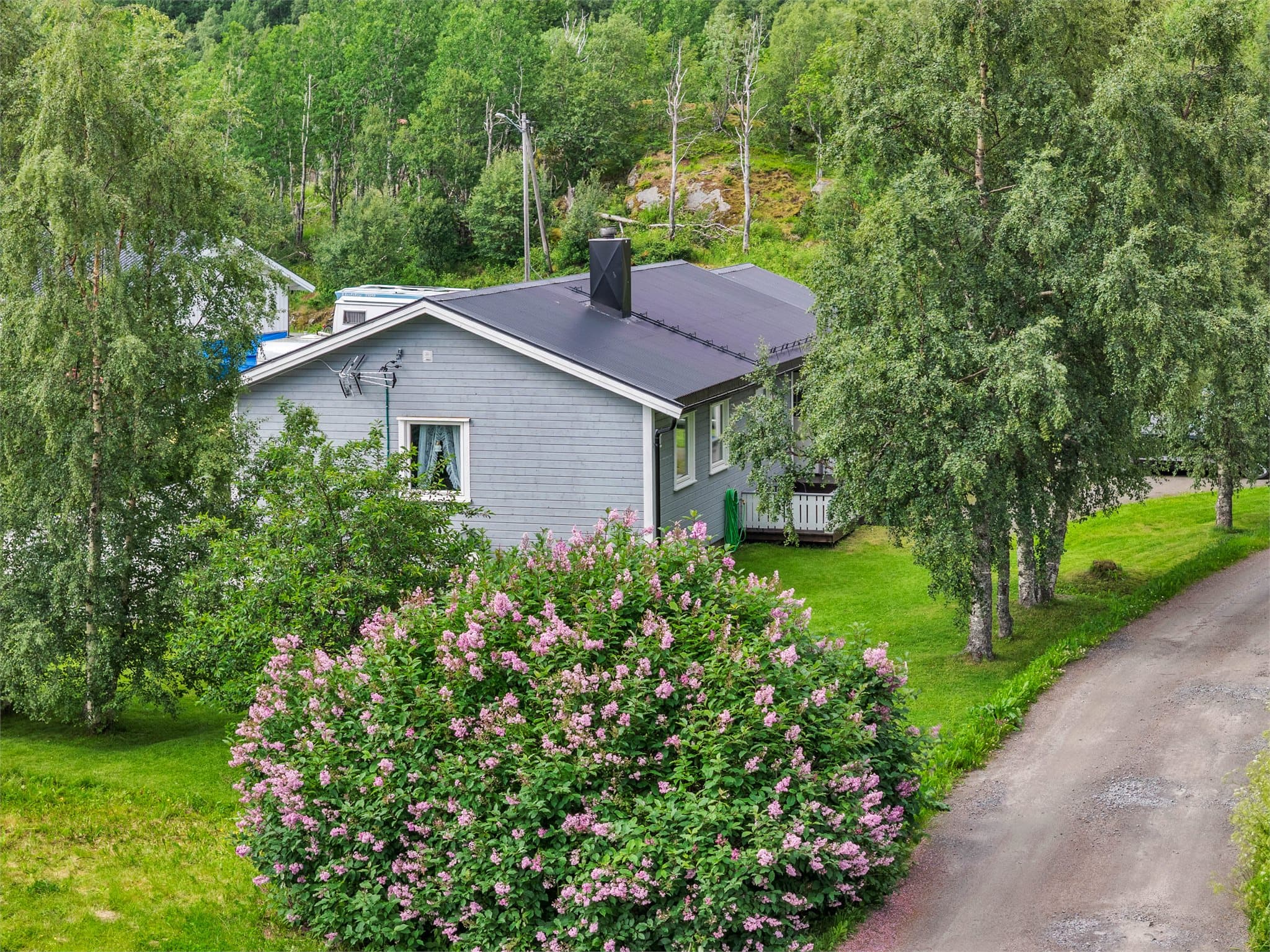 Eneboligen ligger på en flat tomt med gruslagt innkjørsel.