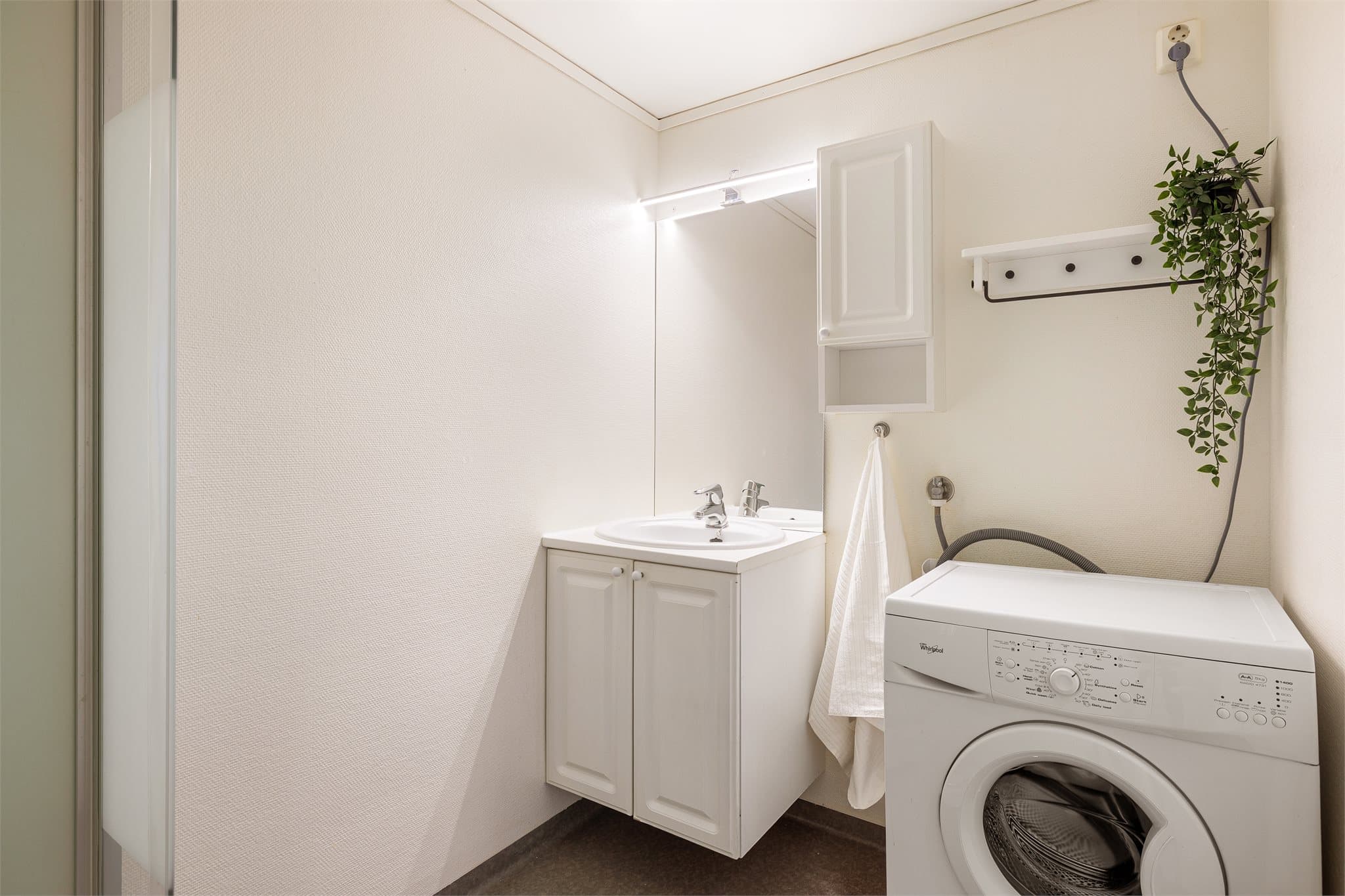 Badet er innredet med servantinnredning, speil, skap, toalett og dusjkabinett.