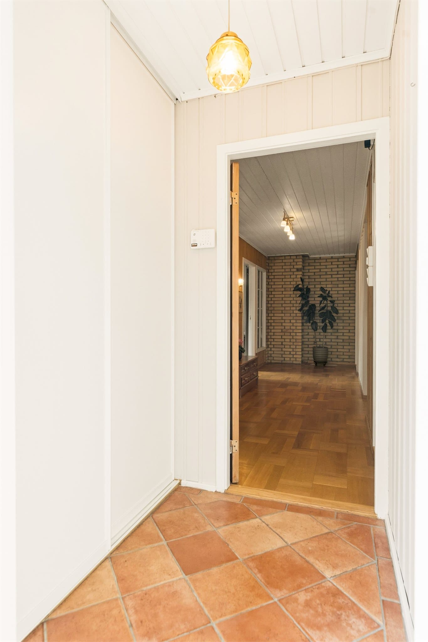 Entré med fliser på gulv og skyvedørsgarderobe.