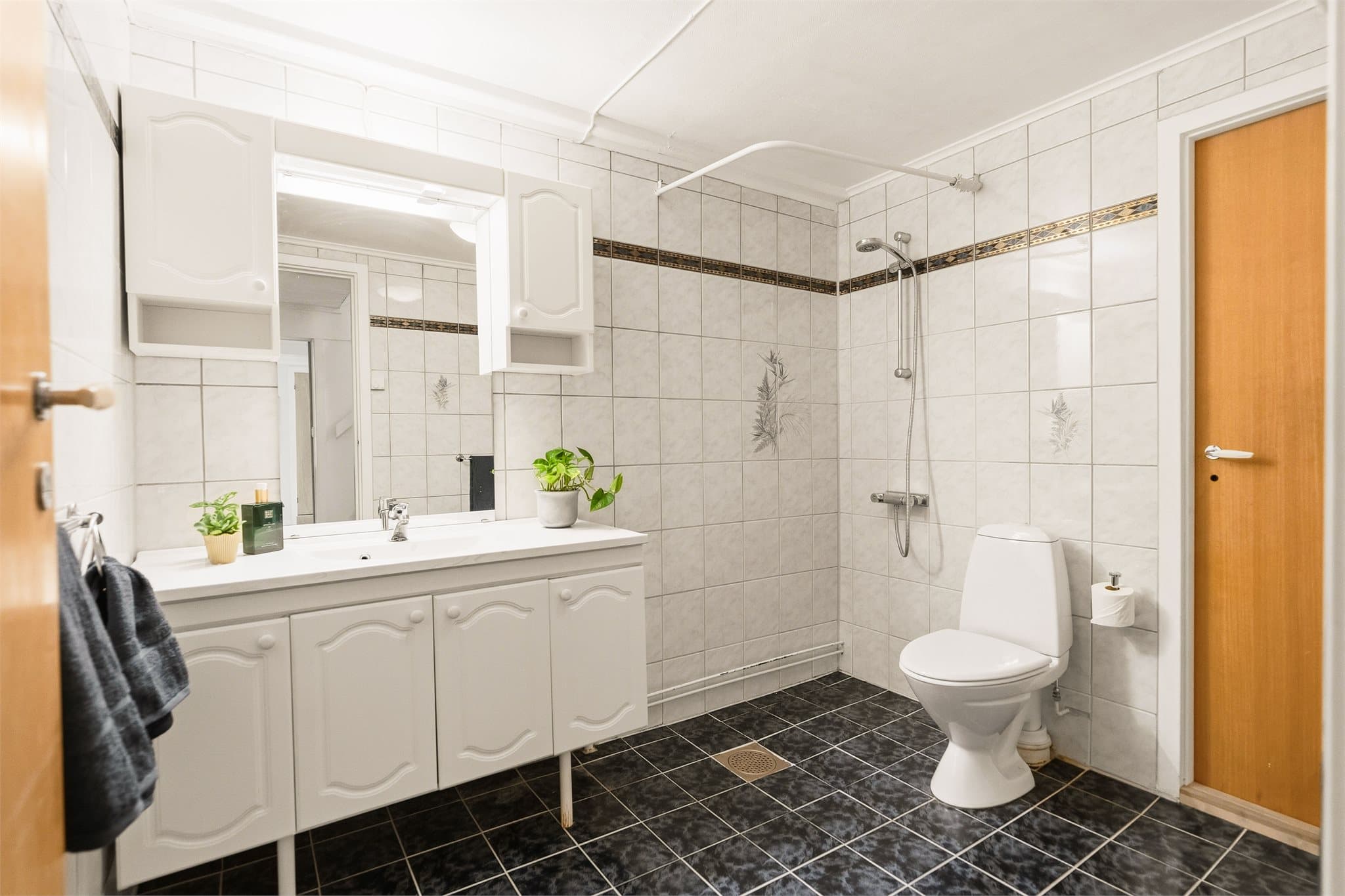 Det andre badet ligger i underetasjen. Det er fliser på gulv og vegger.