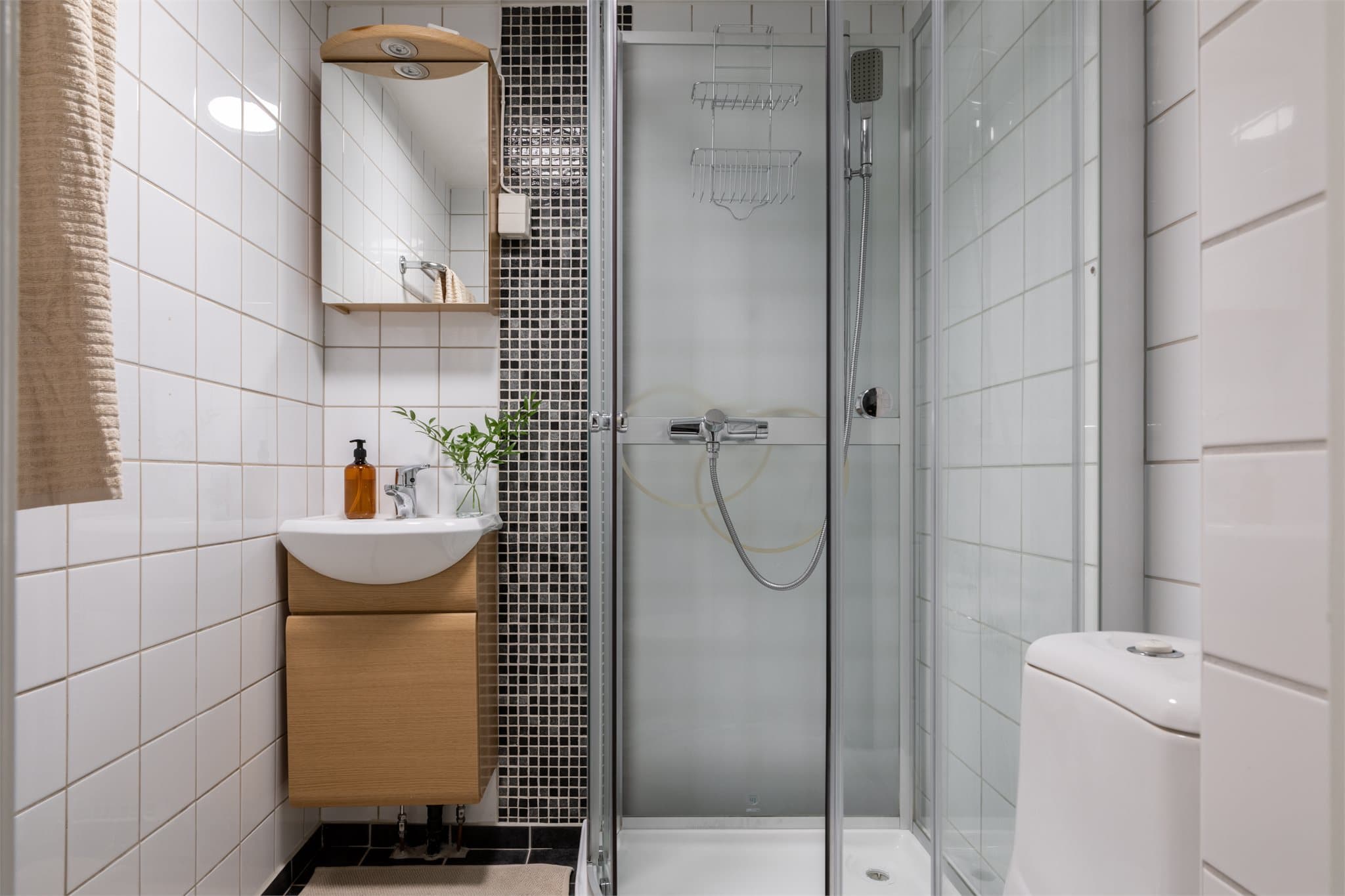 Pent, flislagt baderom med dusjkabinett, toalett og servant med underskap.