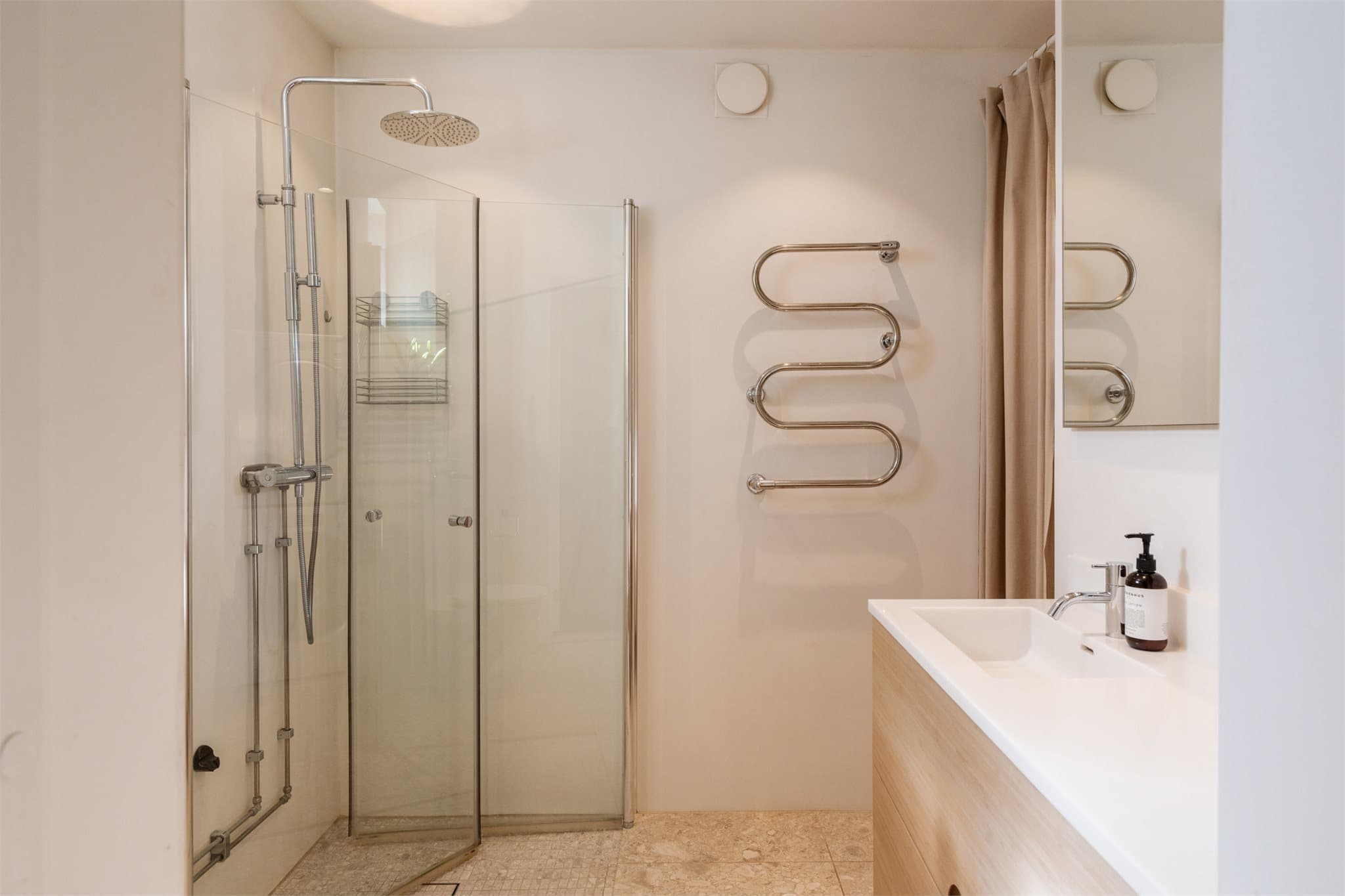 Dusjhjørne med innfellbare glassdører og et moderne togreps blandebatteri.