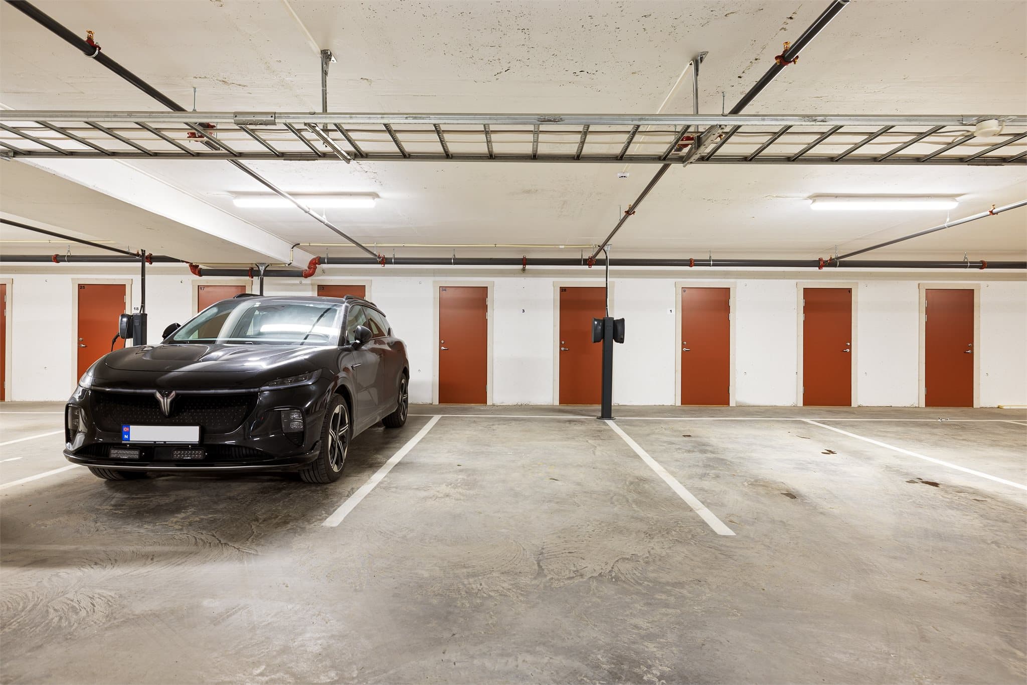 Egen plass i parkeringskjeller. Det er også en ladeboks på parkeringen, men den er ikke fullt installert.