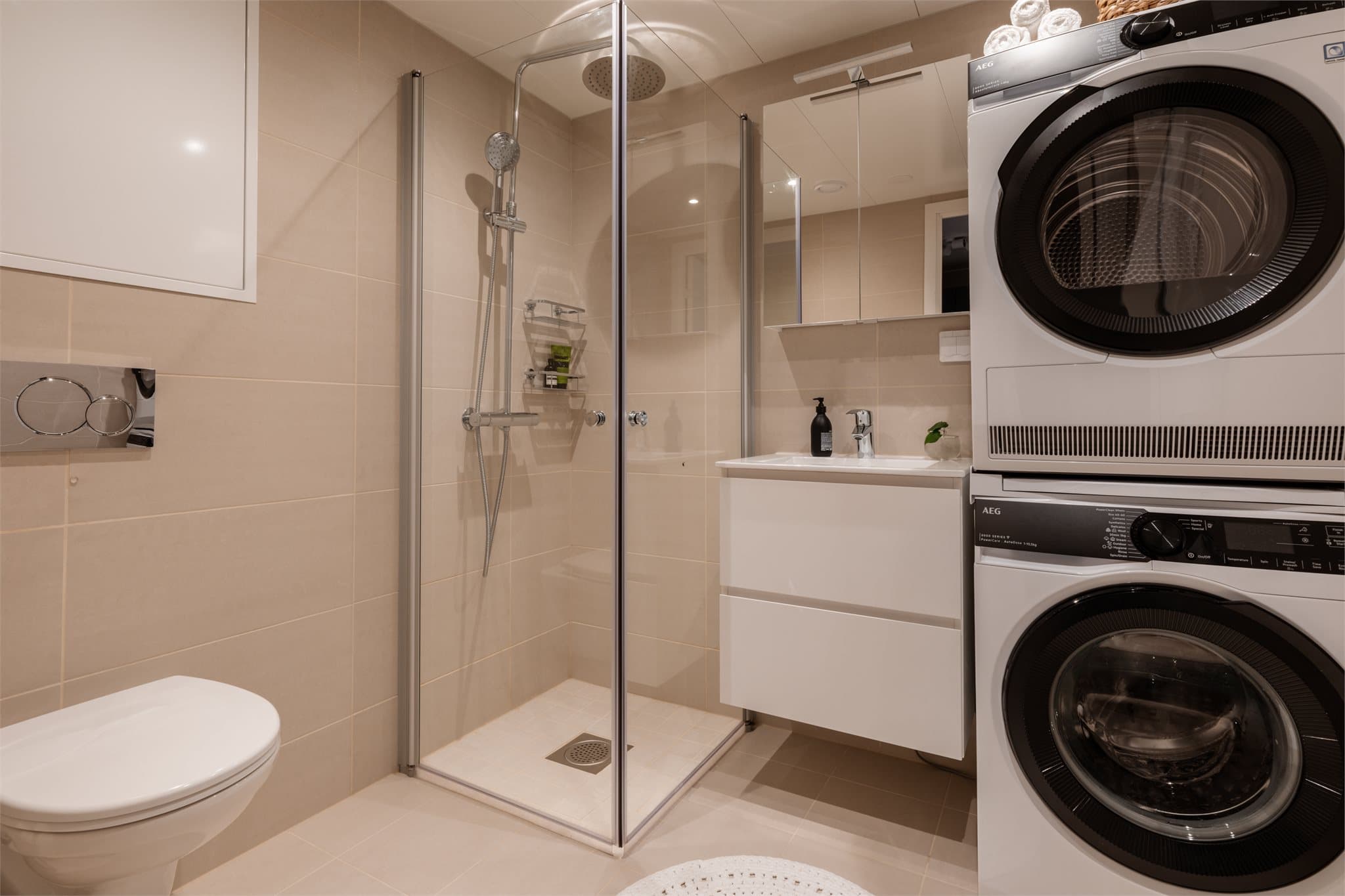 Badet er utstyrt med vegghengt toalett, dusjhjørne og opplegg for vaskesøyle.