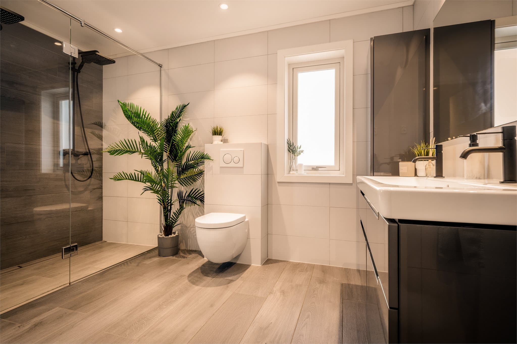 Badet har gulvvarme og utstrakt bruk av downlights i himling. Praktisk vegghengt wc og dobbelservant.