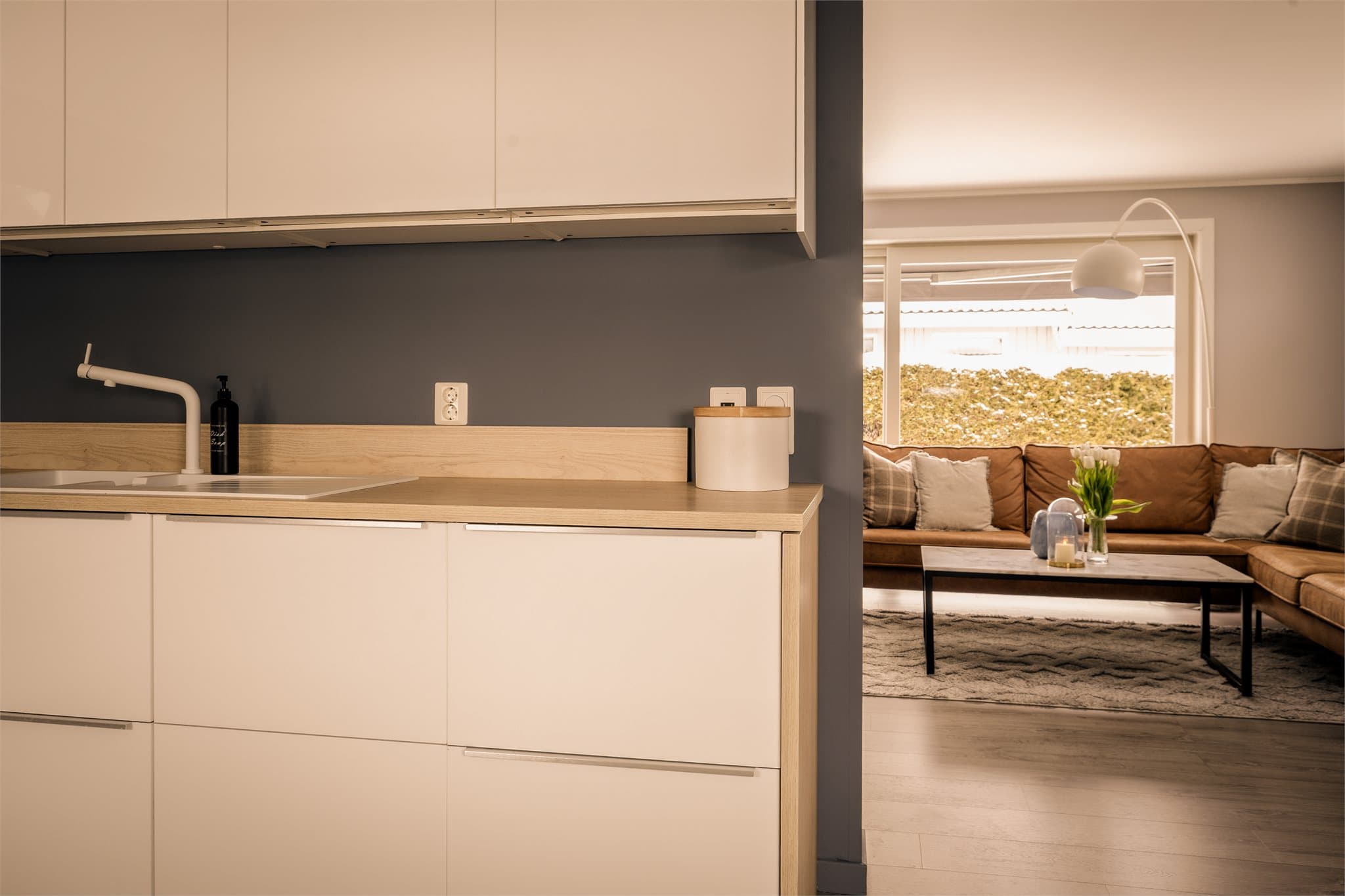 Kjøkkeninnredningen har lyse, høyglans fronter og laminat benkeplate.