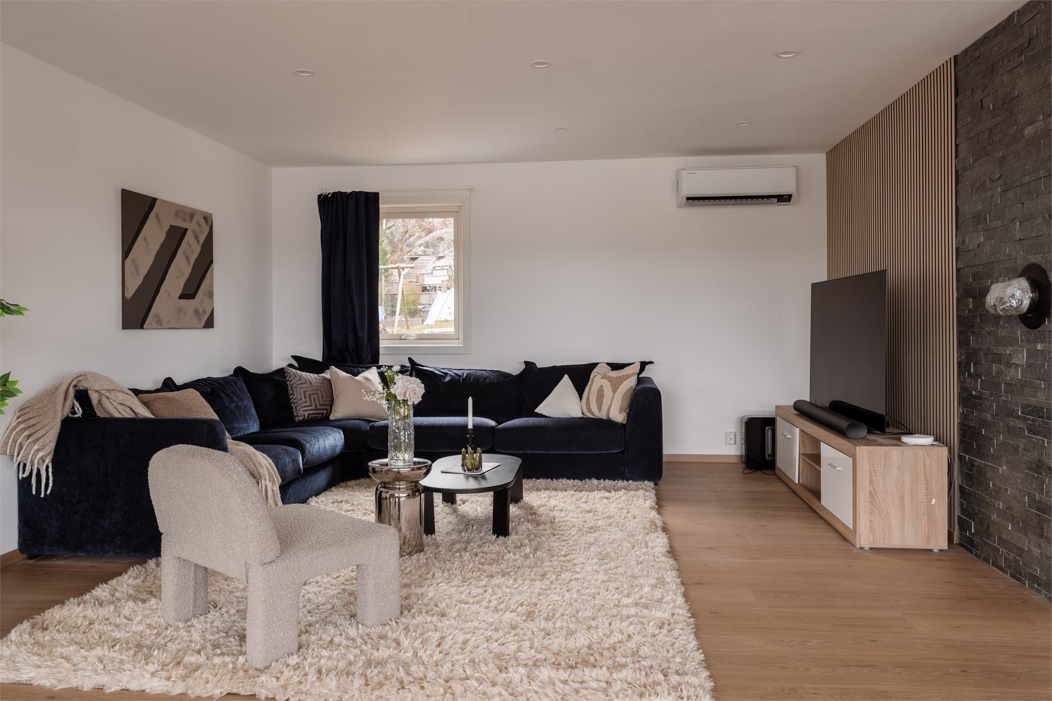 En moderne spilevegg og en fondvegg skaper en stilren ramme for TV-sonen.