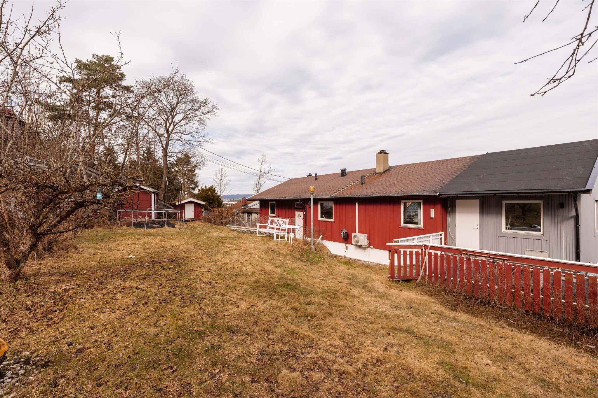 Boligen ligger på en skrå tomt med hage og gode utendørsmuligheter.
