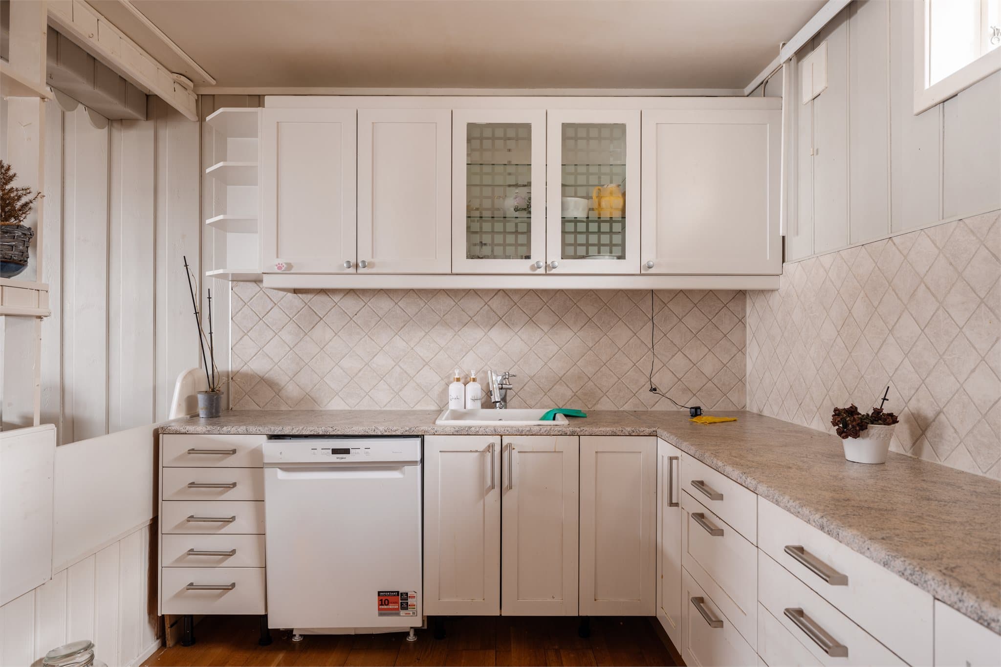 Også dette kjøkkenet er utstyrt med hvitevarer som komfyr og oppvaskmaskin.