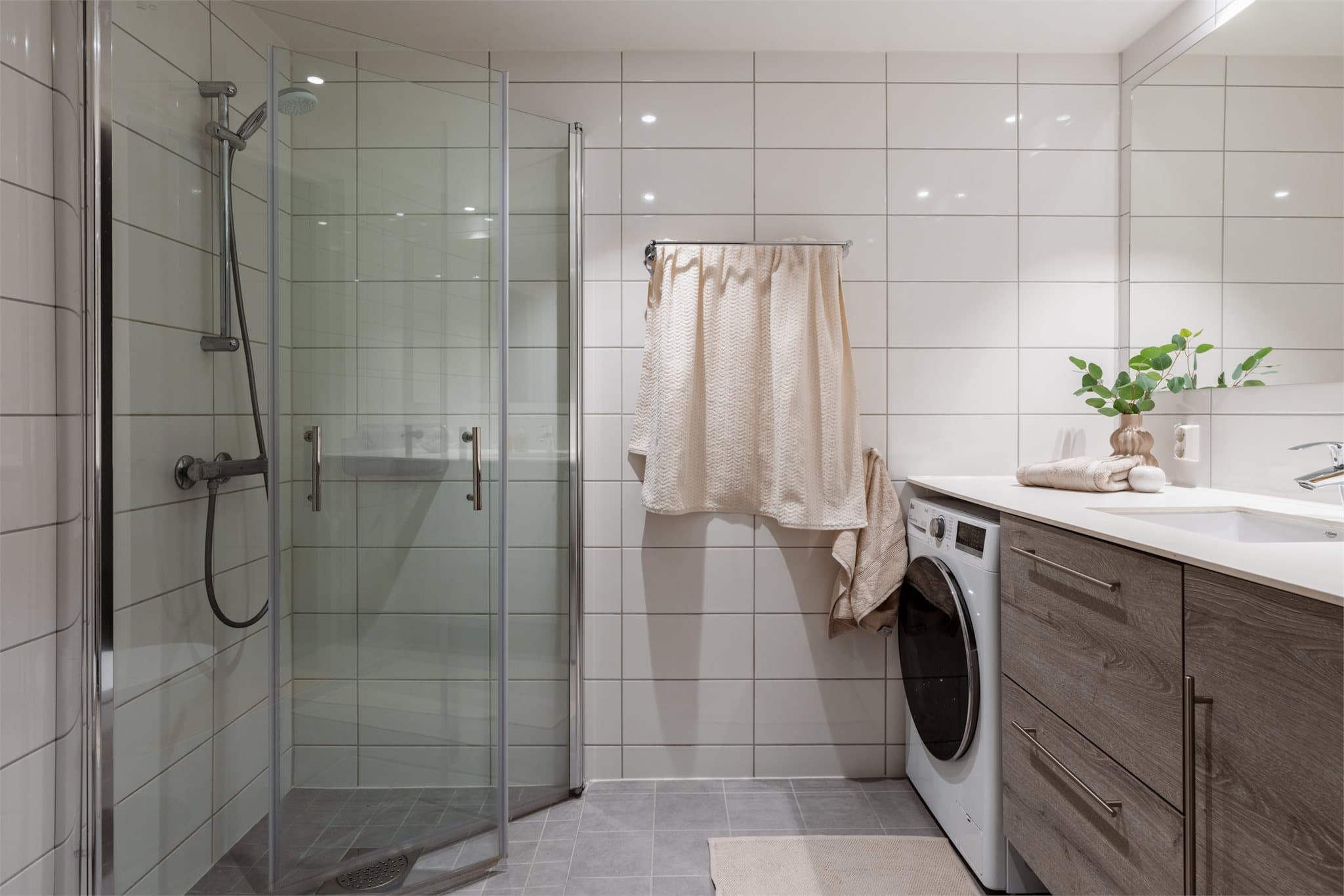 Flislagt baderom med nedsenket dusjnisje og innfellbare glassdører.