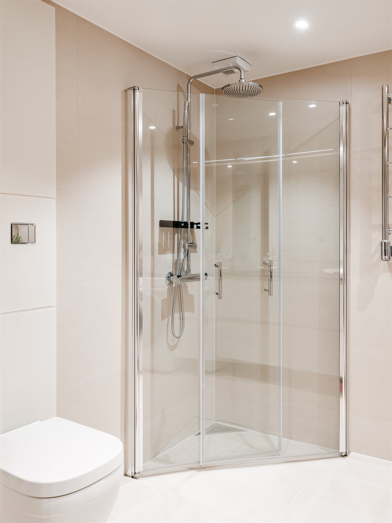 Dusjen er plassert på gulv bak innfellbare glassdører.