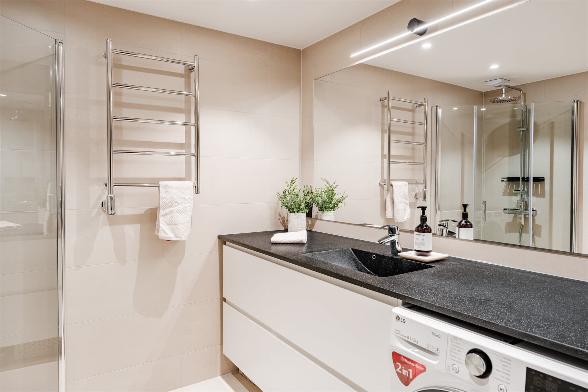 Her har du vegg-til-vegg komposittbenkeplate, håndklestativ med varme og opplegg for vaskemaskin.