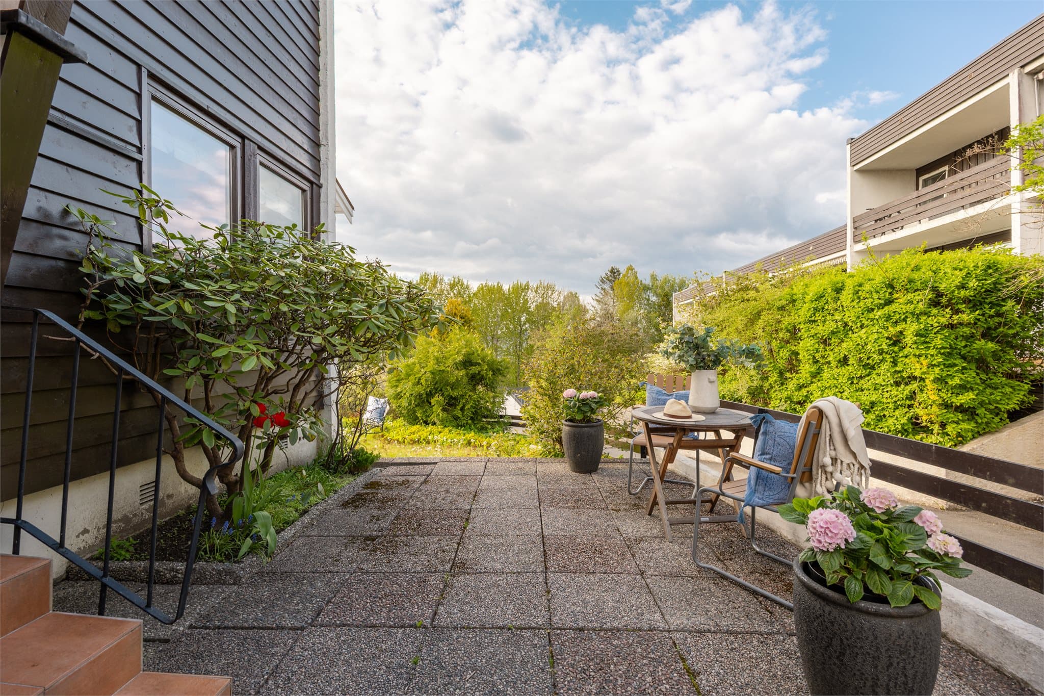 På forsiden av huset er det et praktisk og innbydende område med heller og plass til et lite bord – perfekt for å nyte morgenkaffen i solen.