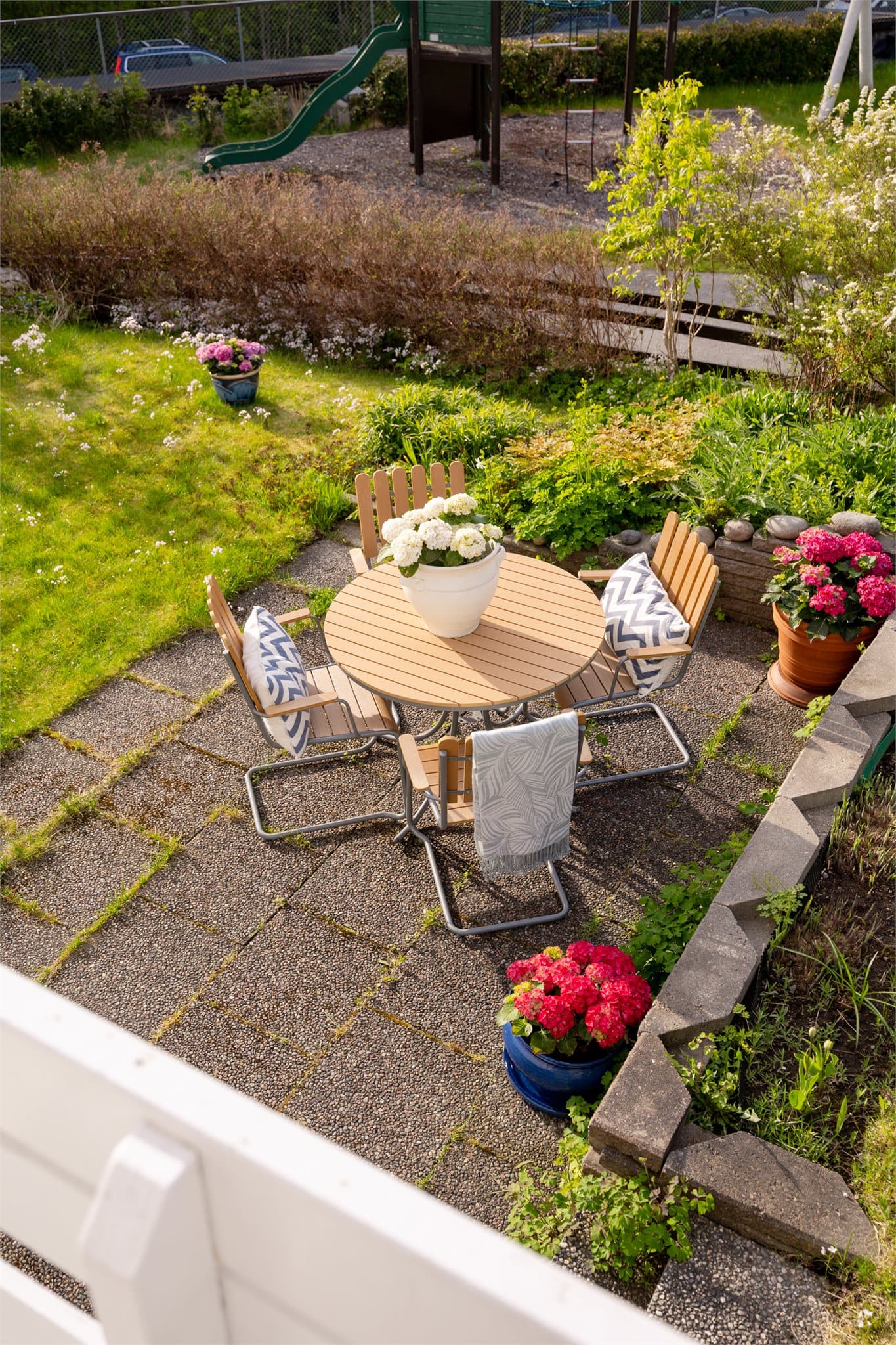 Flere flislagte heller skaper hyggelige soner i hagen, blant annet en lun og skjermet uteplass omkranset av beplantning.