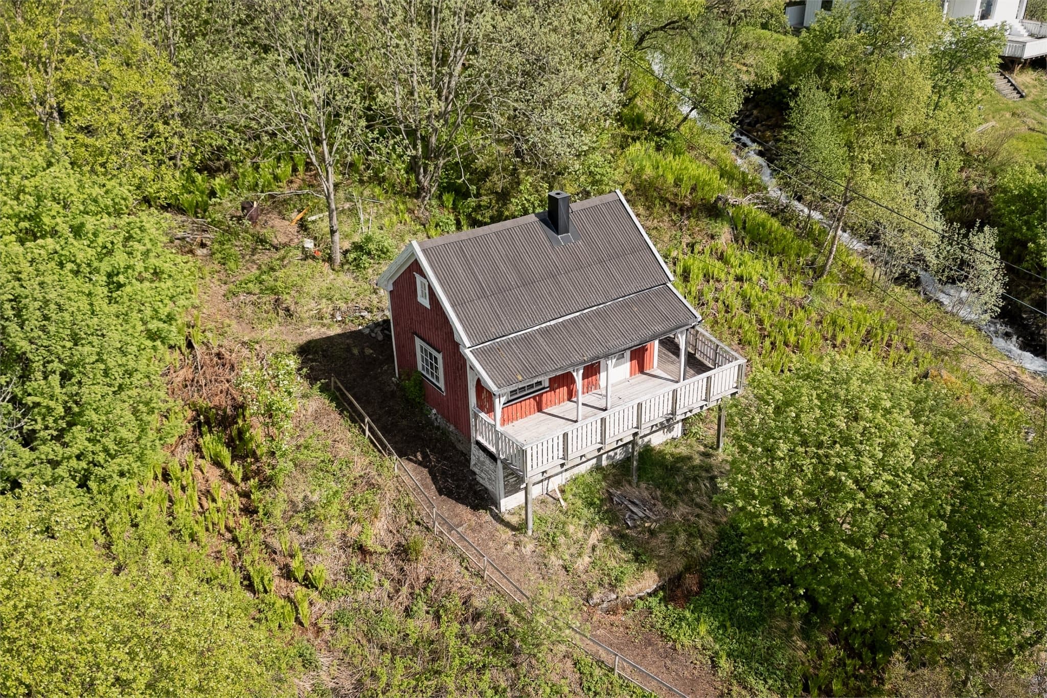 Fritidsboligen er plassert i frodige omgivelser.