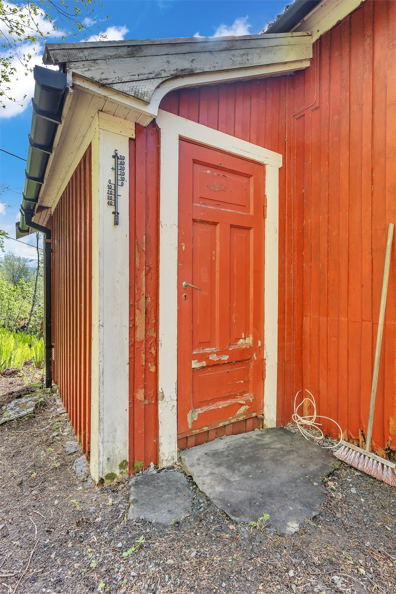Detalj av fasaden med stående bordkledning og tradisjonell, malt ytterdør.
