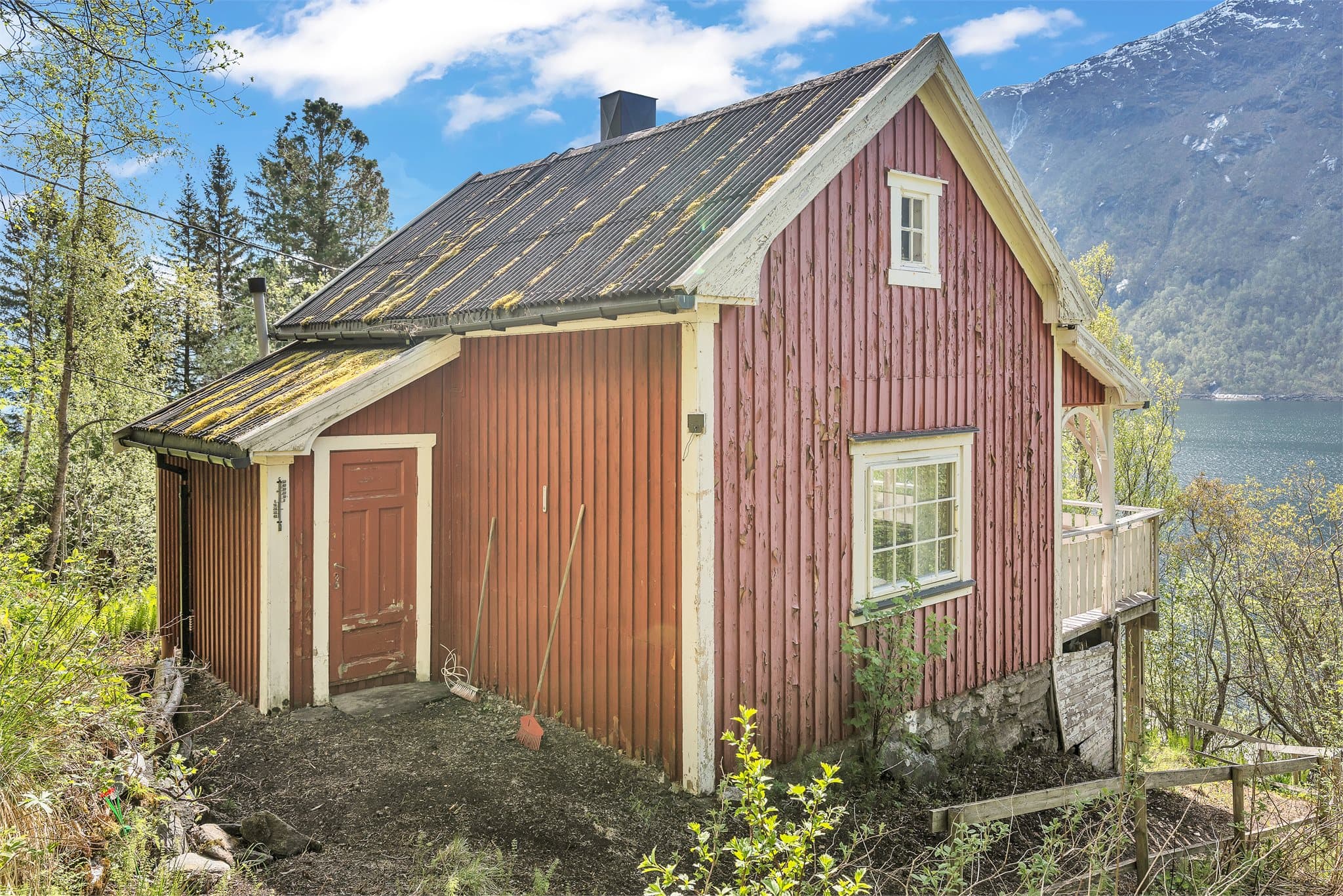 Bygningen hviler på en natursteinsmur, tilpasset det skrånende terrenget.
