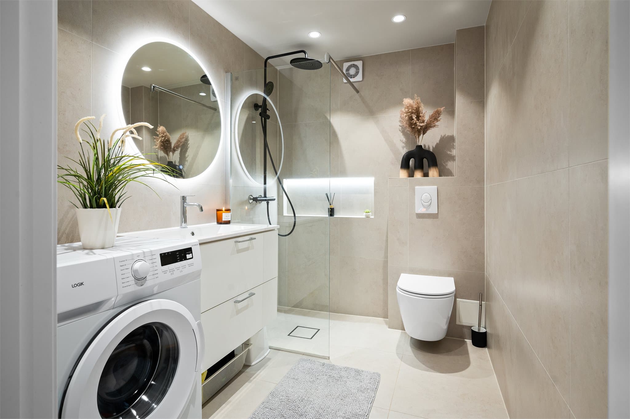 Lekkert og moderne baderom fra 2024 med stilren utførelse, flislagte overflater og vannbåren gulvvarme. Nedsenket dusjsone med glassdører, vegghengt toalett og praktisk servantinnredning gir et rent og funksjonelt uttrykk.