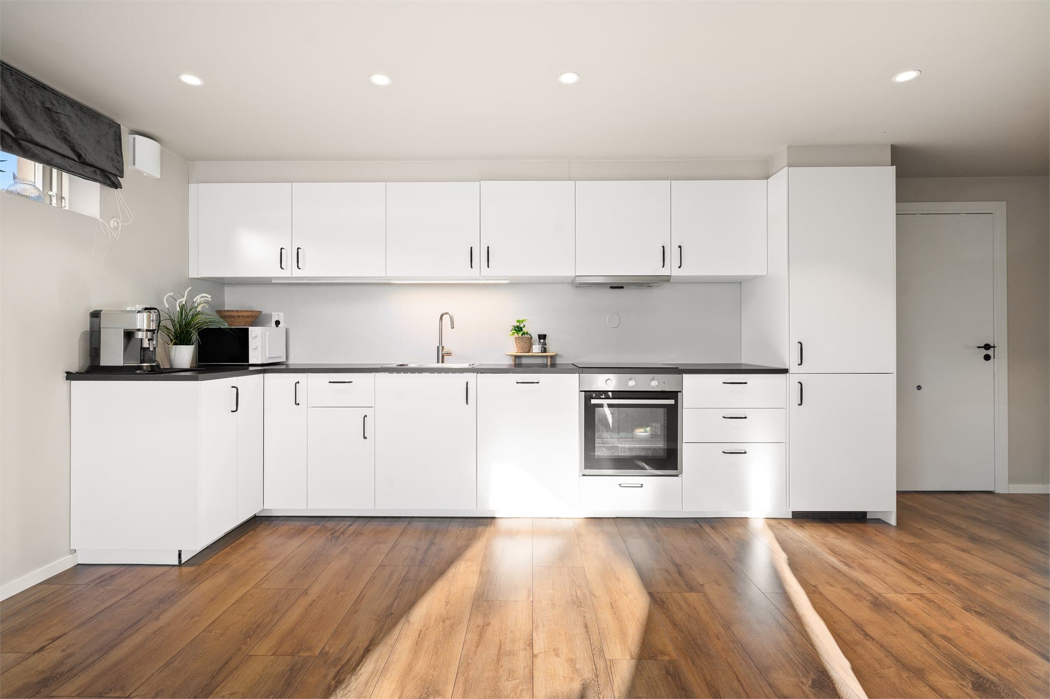 Stilrent og funksjonelt kjøkken med hvite fronter og god skap- og benkeplass.