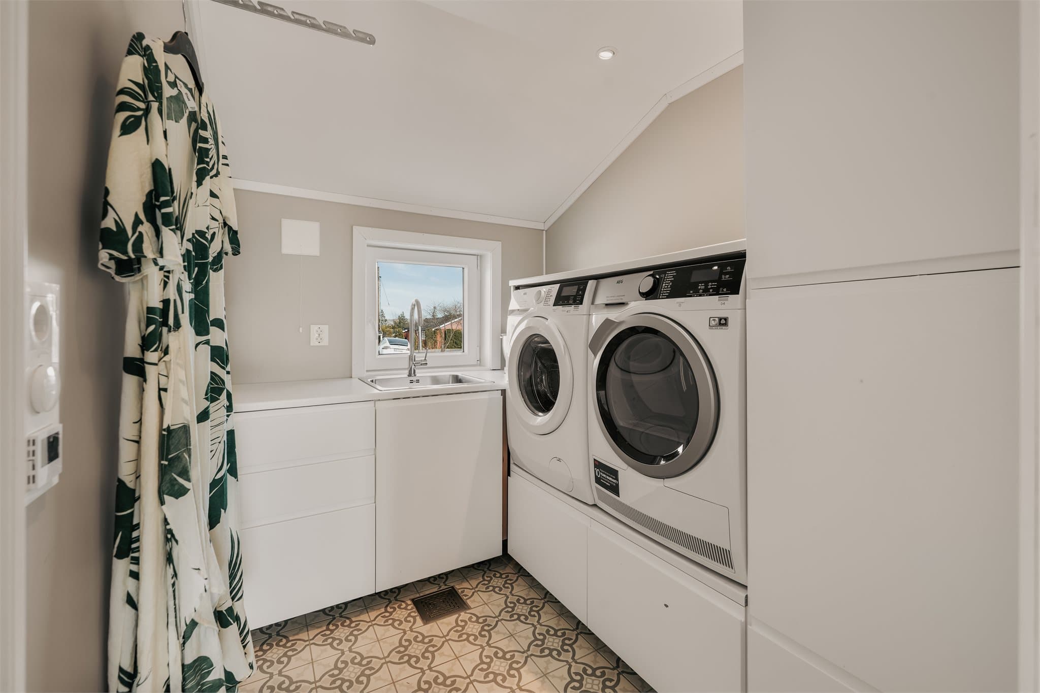 Praktisk vaskerom med opplegg for vaskemaskin og tørketrommel. Det er i tillegg godt med skapplass.