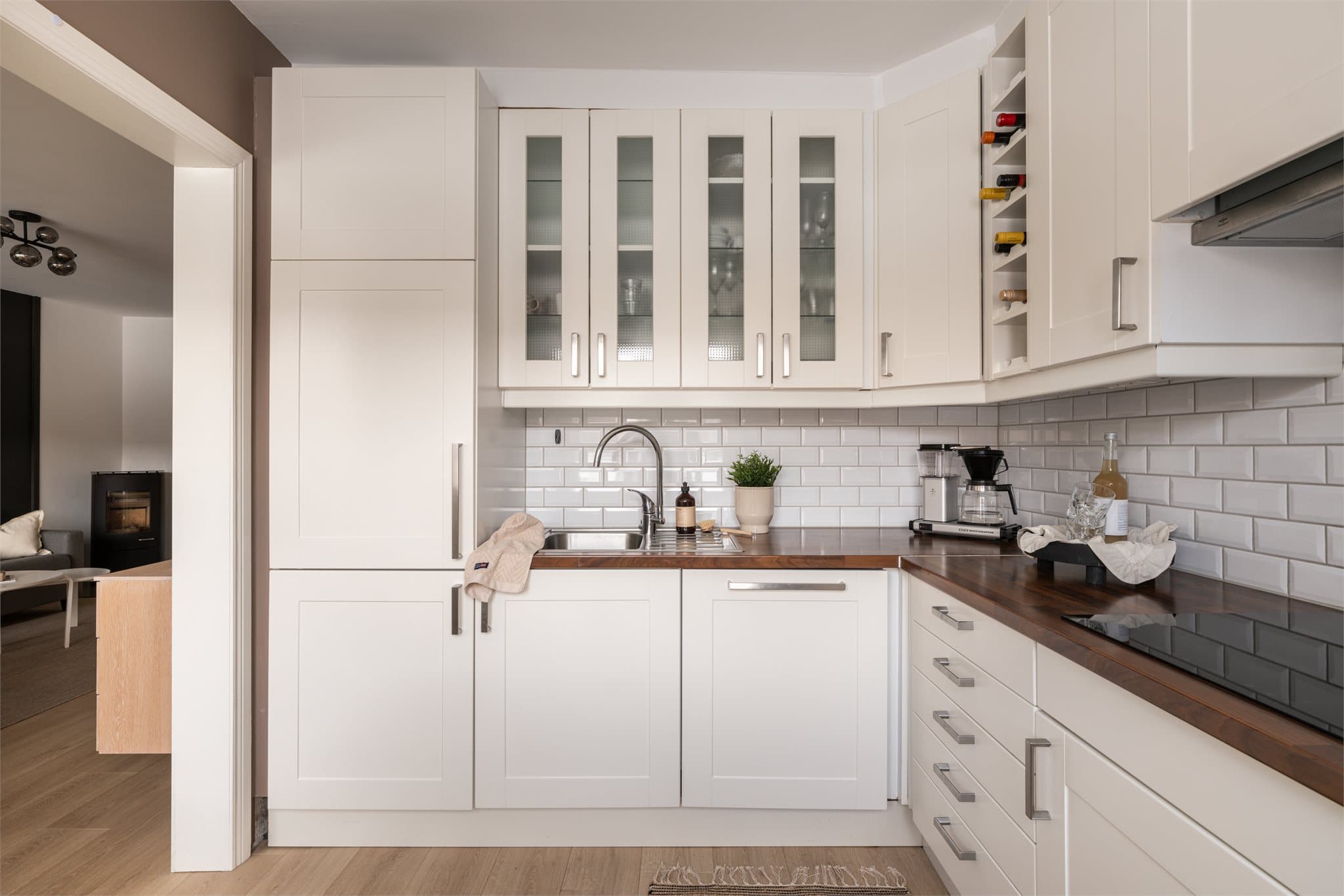 Pent, tidløst kjøkken med profilerte hvite fronter og integrerte hvitevarer.