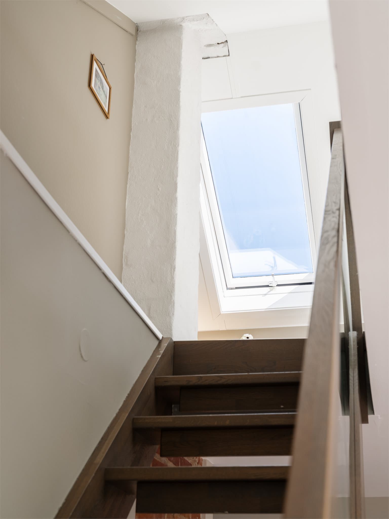 Tretrapp med glassrekkverk leder fra stuen opp til loftsetasjen.