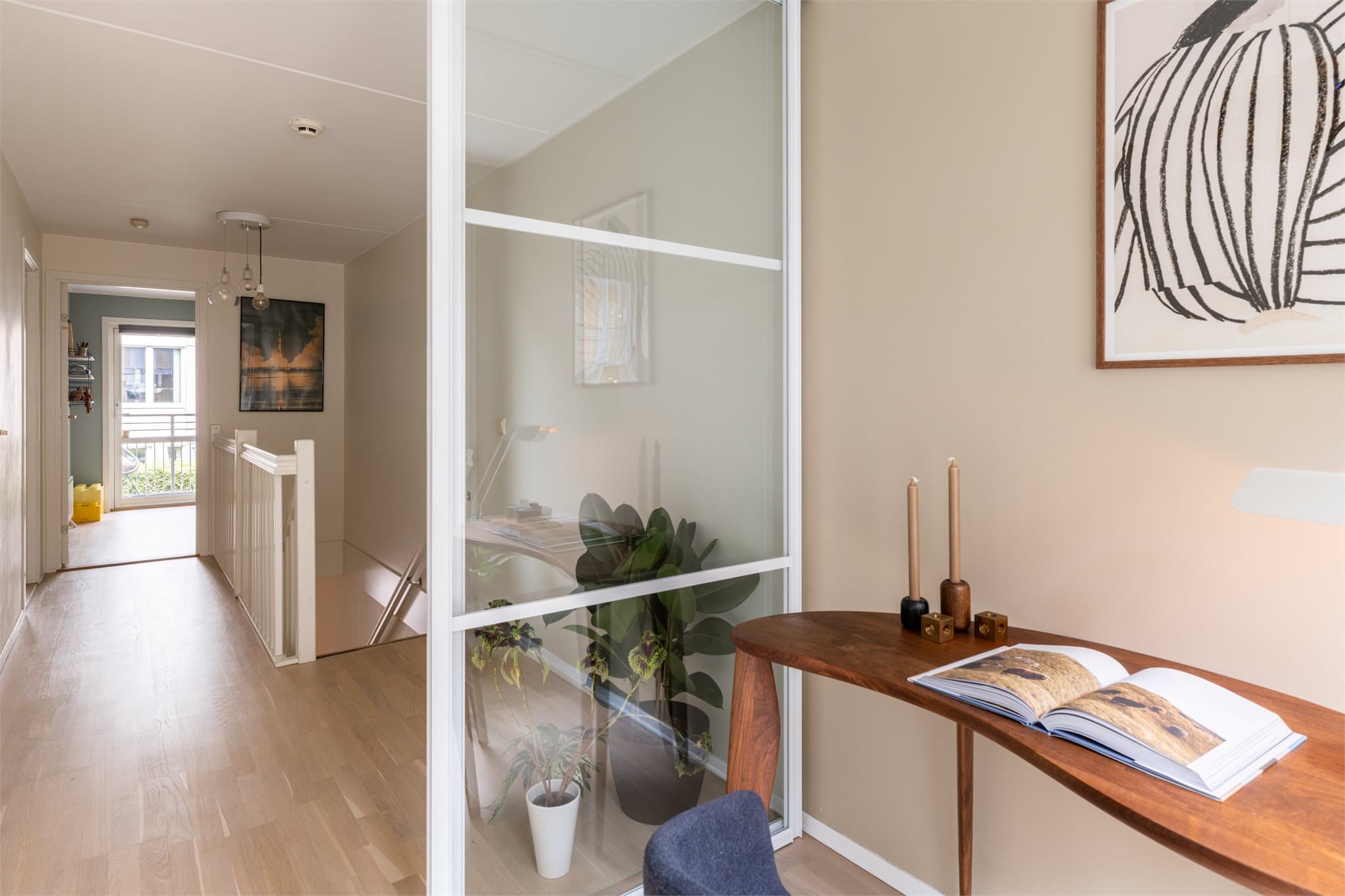 En smart utnyttelse av plassen som gir en funksjonell arbeidsplass med skyvedører i glass som slipper lys inn i boligen/trappegangen men skjermer for lyd.