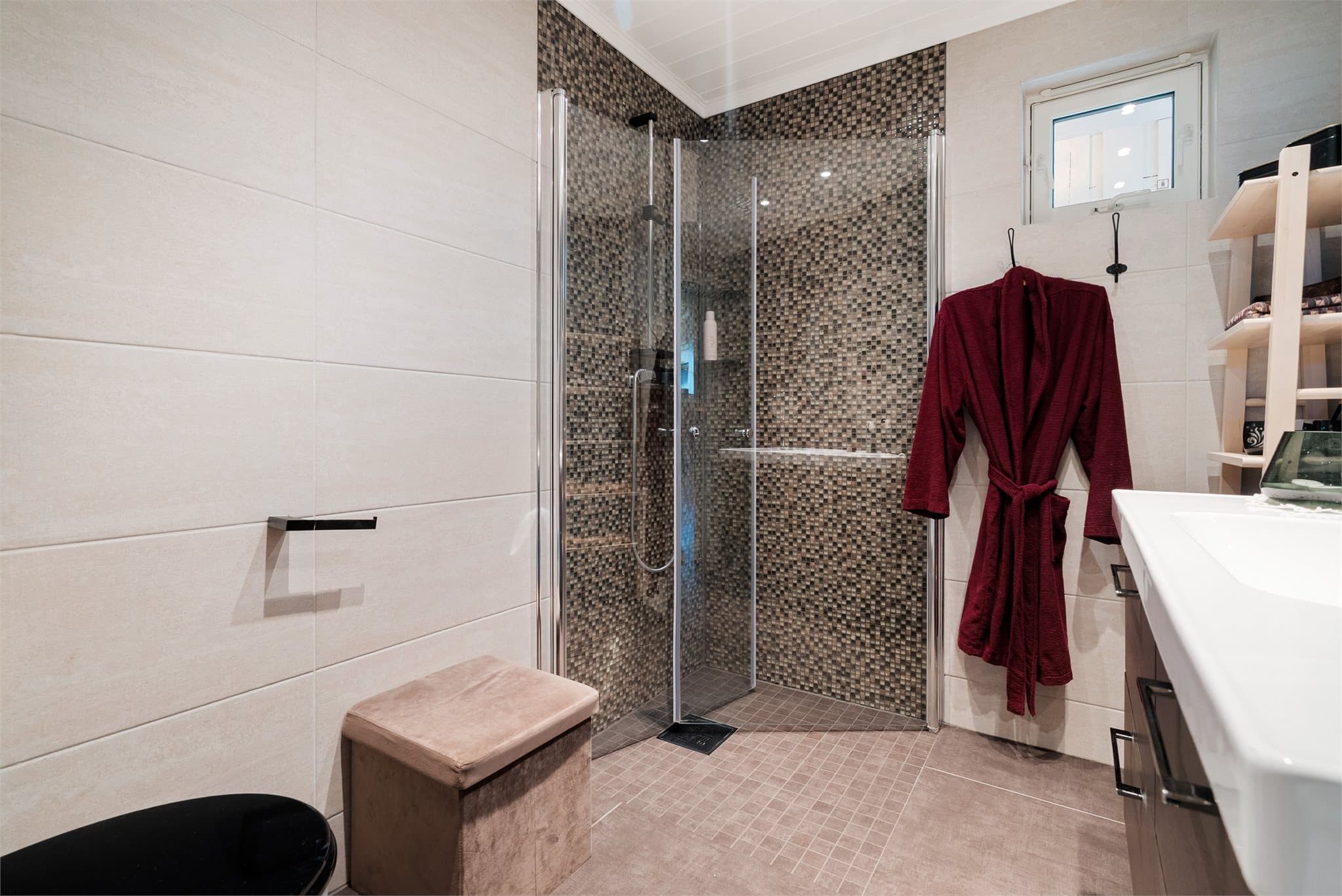 Badet i hovedetasjen er utstyrt med toalett, servantinnredning og dusjhjørne, mens et separat vaskerom gir praktisk plass til klesvask.