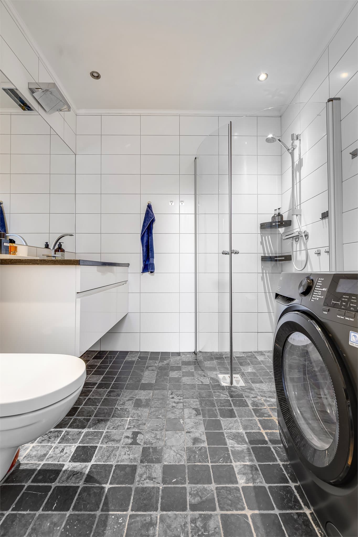 Badet har mørke 10x10 fliser på gulv og lyse 20x40 fliser på veggene.