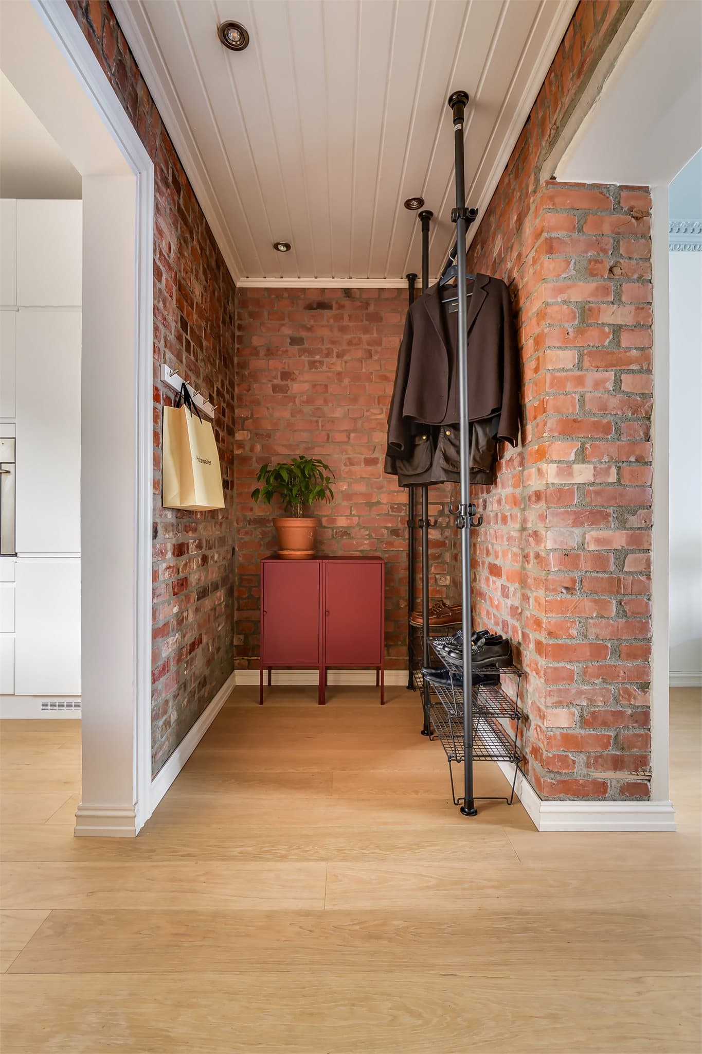 Entréen ønsker velkommen med en eksponert teglvegg som understreker leilighetens karakter.