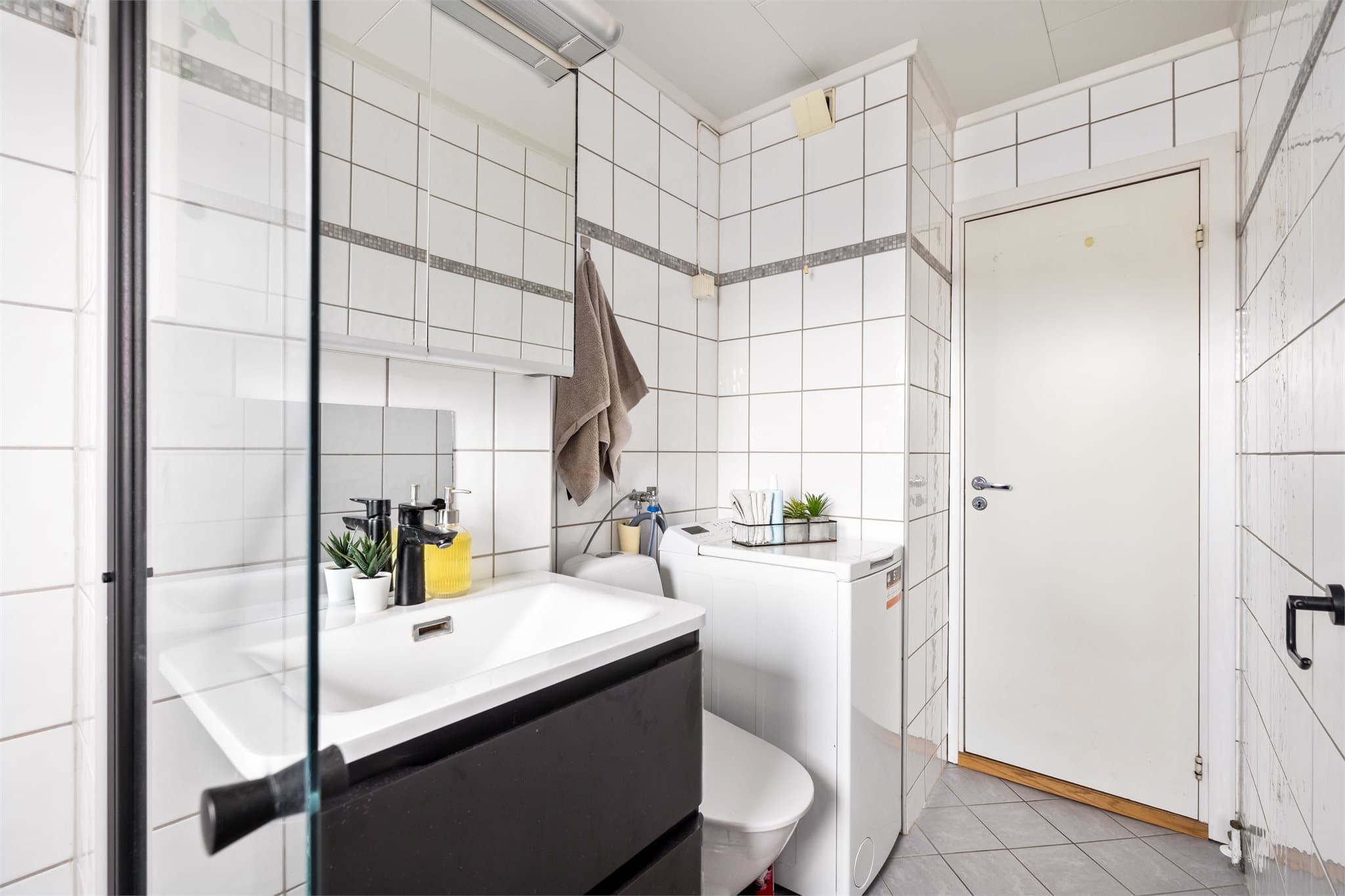 Badet er utstyrt med dusjhjørne, servantinnredning, toalett og har opplegg for vaskemaskin.