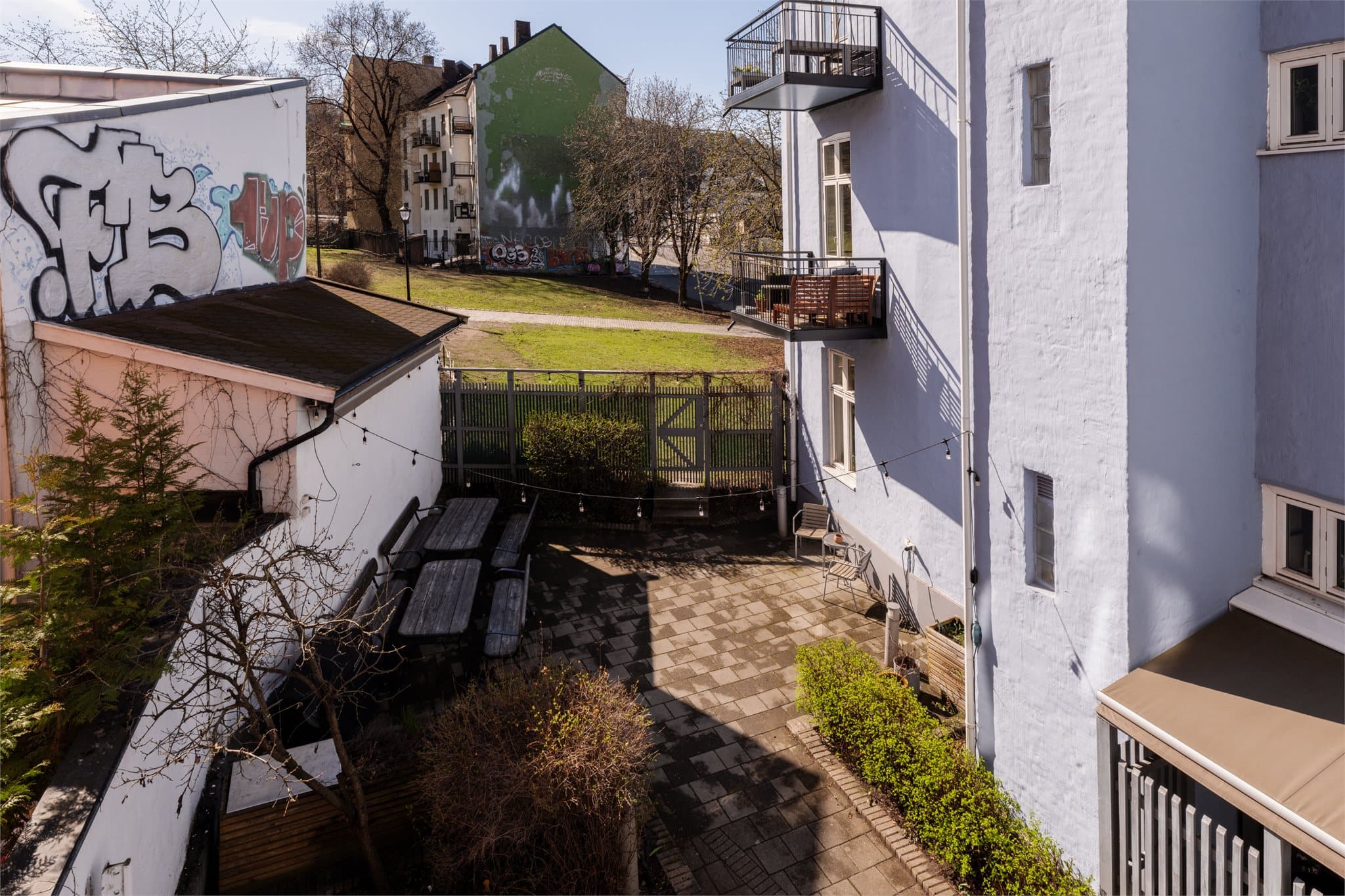 Fra balkongen ser du ned på Ruinparken og borettslagets felles uteplass med sittegrupper.
