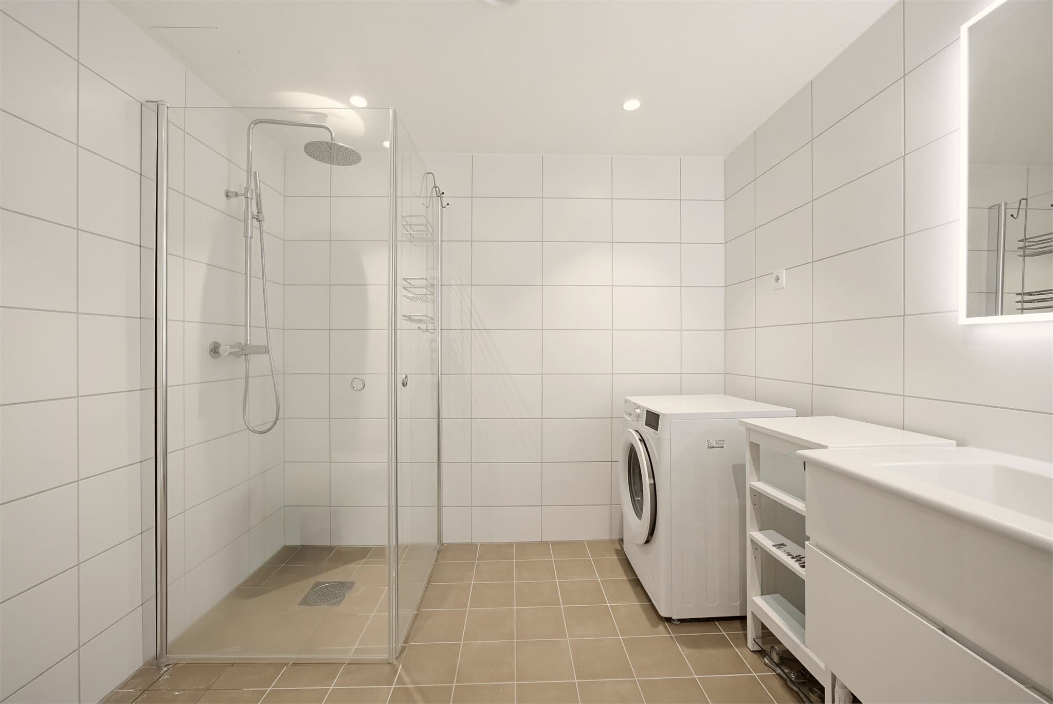 Badet har en moderne utførelse med grå fliser på gulv og hvite fliser på veggene, som gir et stilrent og tidløst uttrykk.