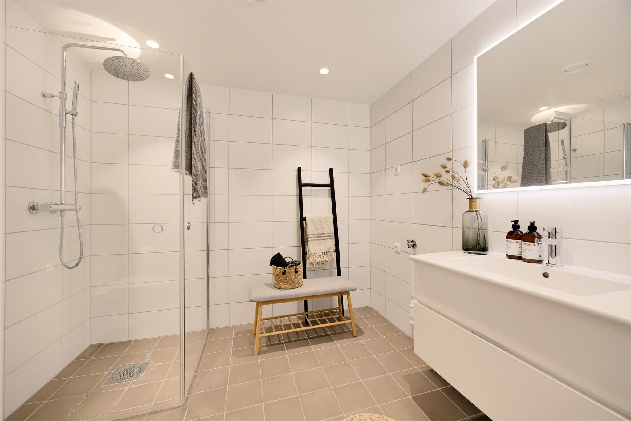Badet har en moderne utførelse med grå fliser på gulv og hvite fliser på veggene, som gir et stilrent og tidløst uttrykk.