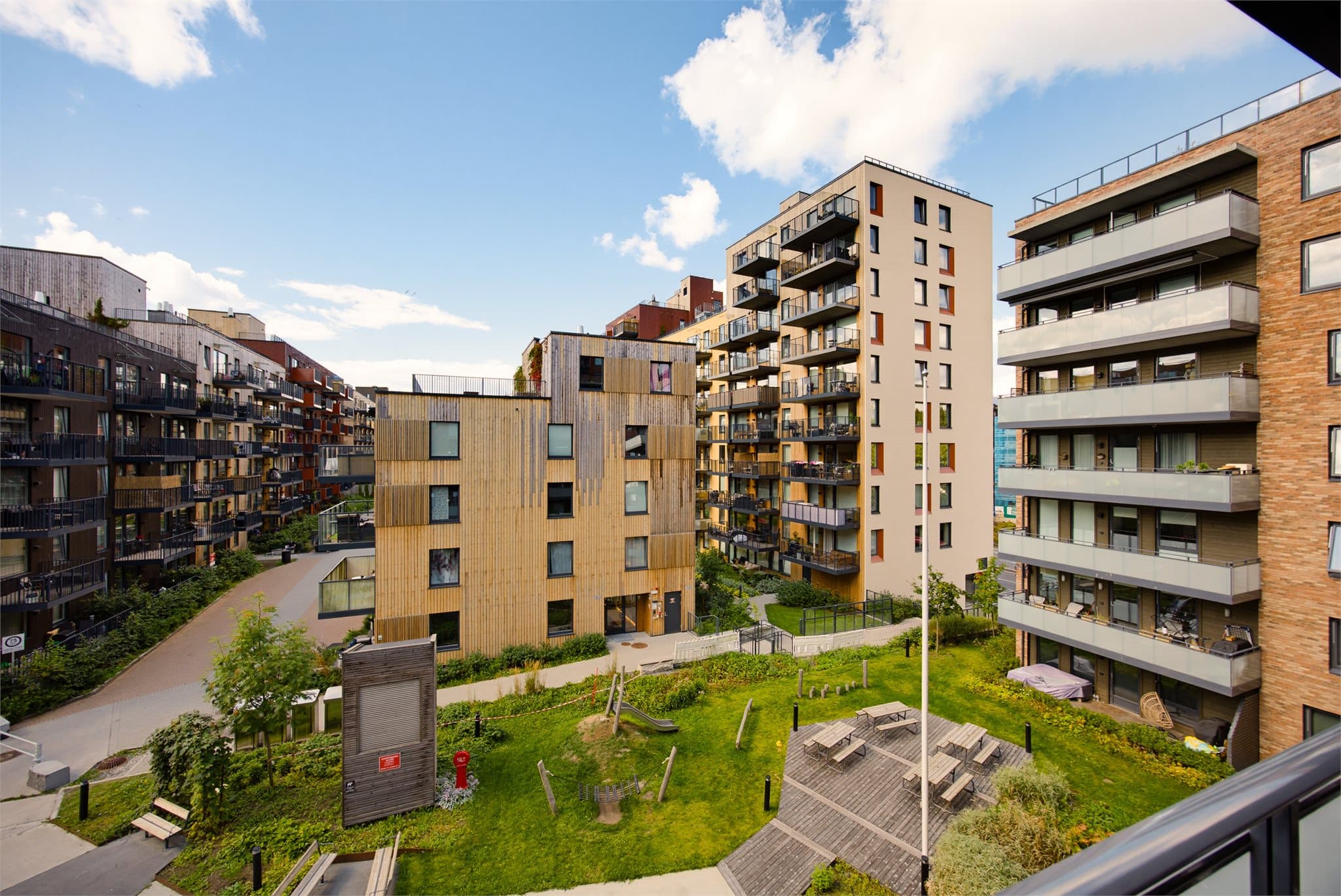 Utsyn fra balkongen mot koselig grøntområde og lekeplass for barna.