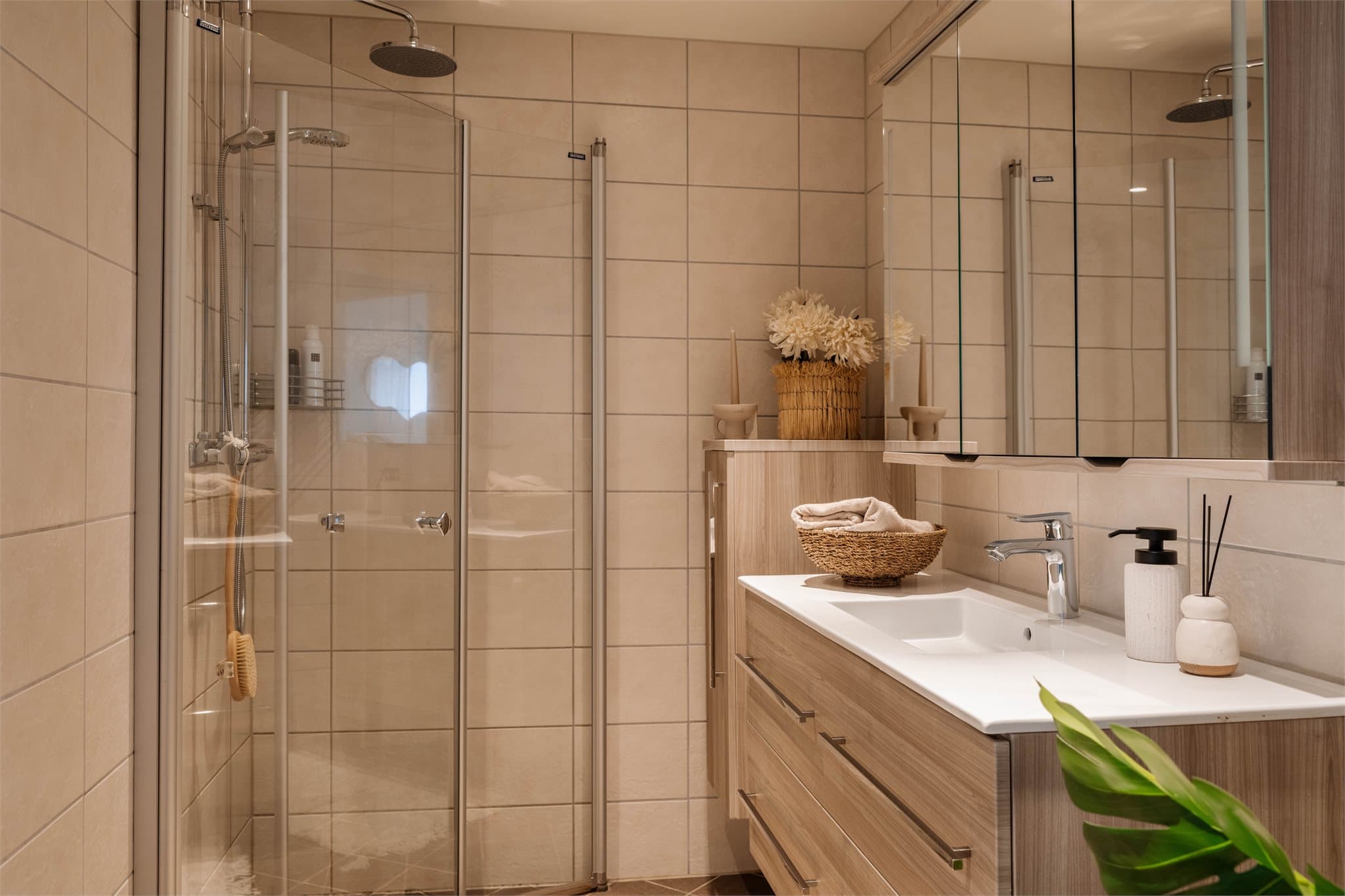 Her er det dusjhjørne med svingbare glassdører, servantinnredning, speilskap og opplegg for vaskemaskin.